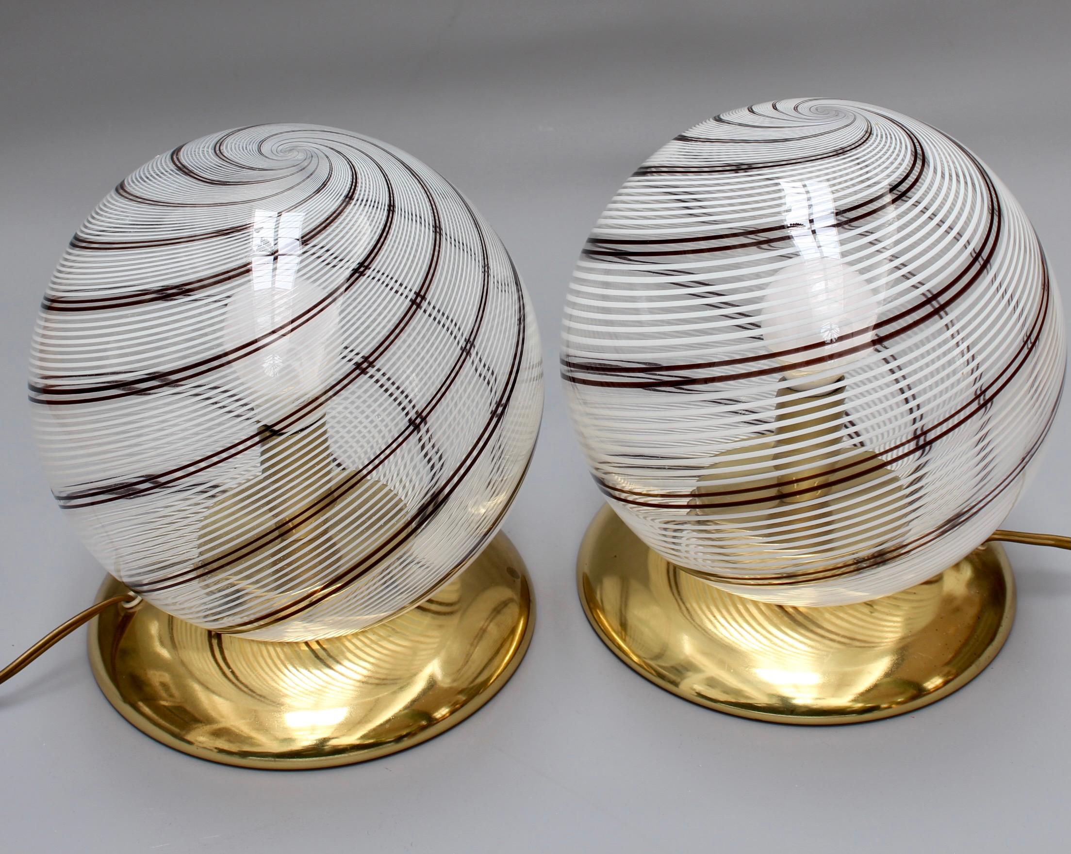 Pair of blown Murano clear glass globe table lamps (circa 1970s) in the style of Paulo Venini. Modernist and elegant, these blown glass globe lamps provide a source of lighting which is both functional and decorative. The stripe effect was ahead of