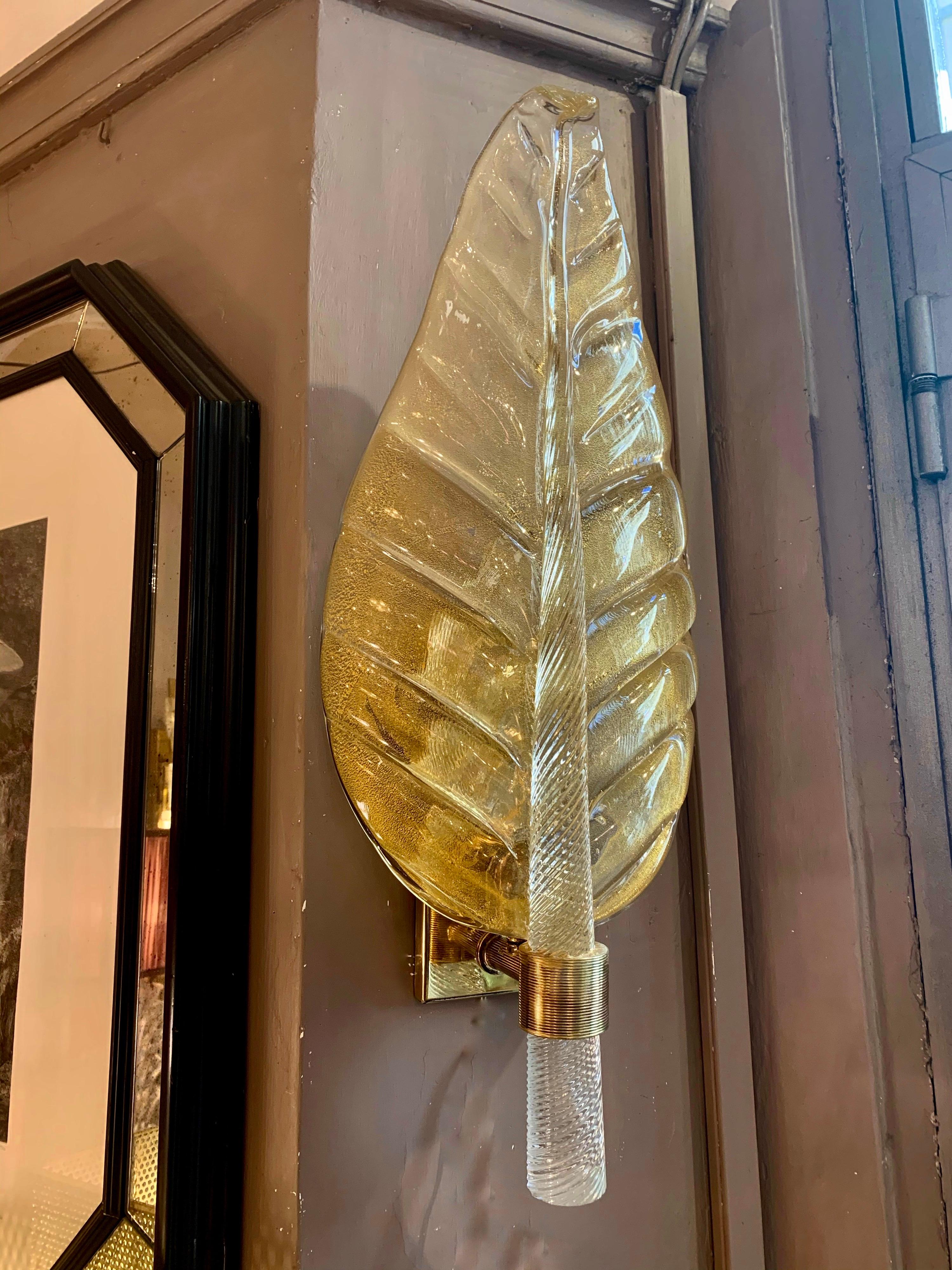 Pair of Murano glass gold leaf sconces, brass structure, one bulb each lamp. These sconces are in Murano hand blown thick glass with gold flecks, the stem of the leaf is in full transparent torchon glass.
