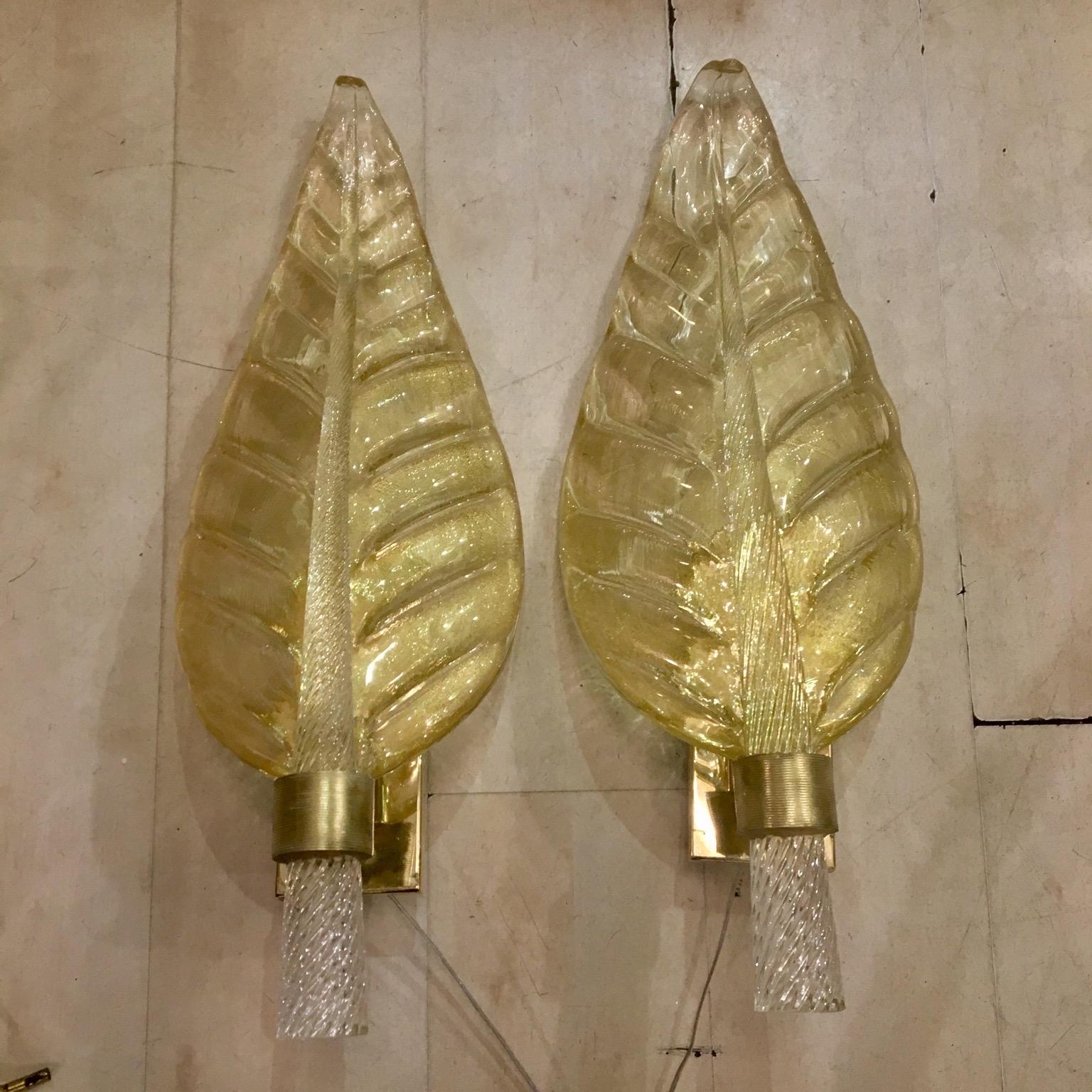 Pair of Murano glass gold leaf sconces, brass structure, one bulb each lamp. These sconces are in Murano hand blown thick glass with gold flecks, the stem of the leaf is in full transparent torchon glass.