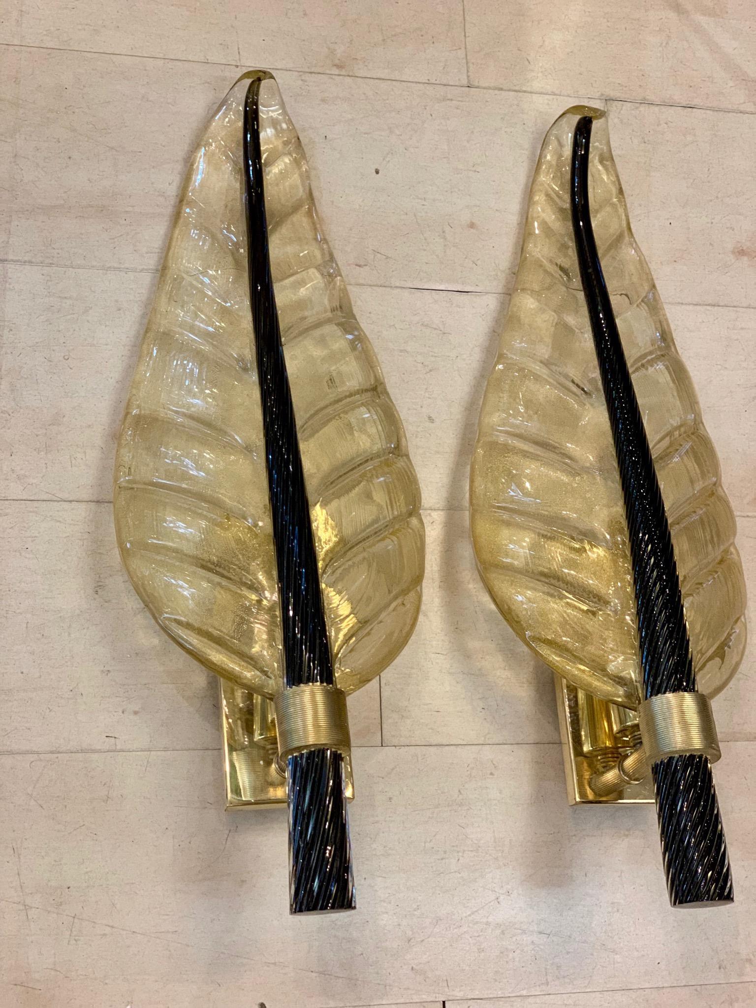Pair of Murano glass gold leaf sconces with black torchon glass leaf stem, brass structure, one bulb for lamp.
These sconces are in Murano hand blown thick glass with gold flecks, the stem of the leaf is in full black torchon Murano glass.