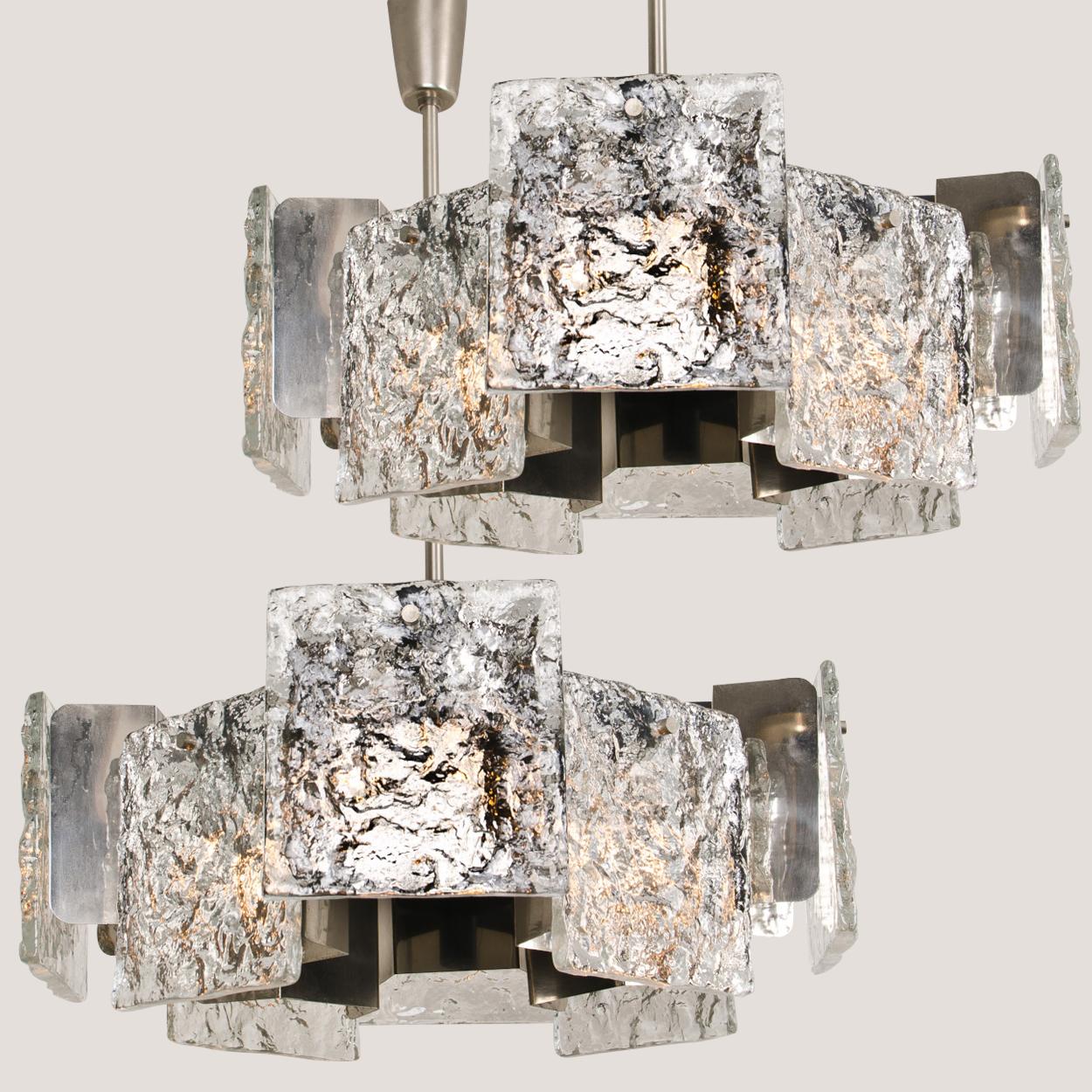 This pair of high-end chandeliers where designed and manufactured by J. T. Kalmar, Austria, circa 1960. Each fixture takes 16 bulbs and features eight handmade solid glass elements made from Murano glass. The frame is made from chrome-plated and