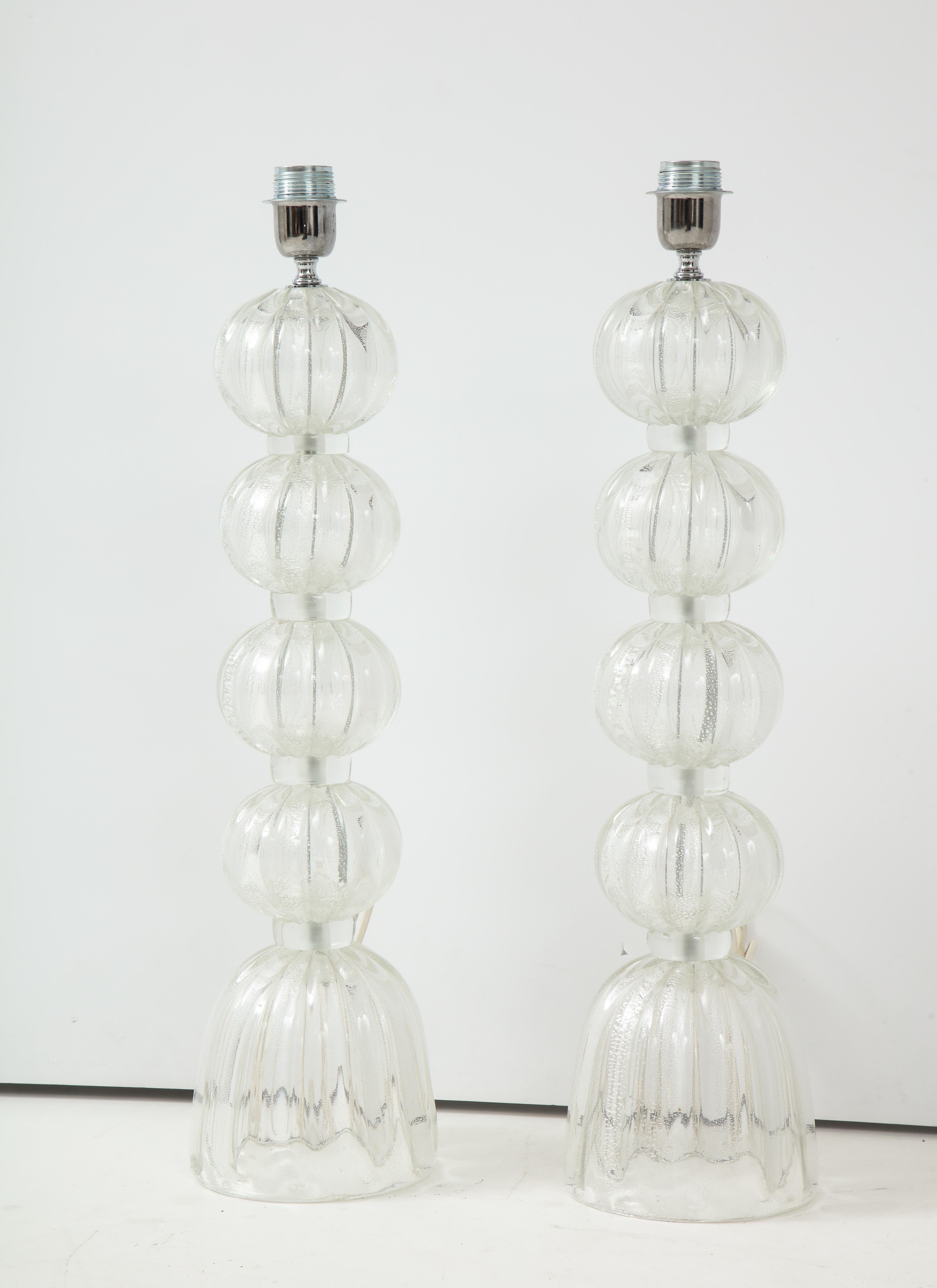 A pair of chic lamps in Murano glass composed of ribbed glass globes separated by glass rings. The clear glass goes with any color scheme and adds a bit of glamour to any space!