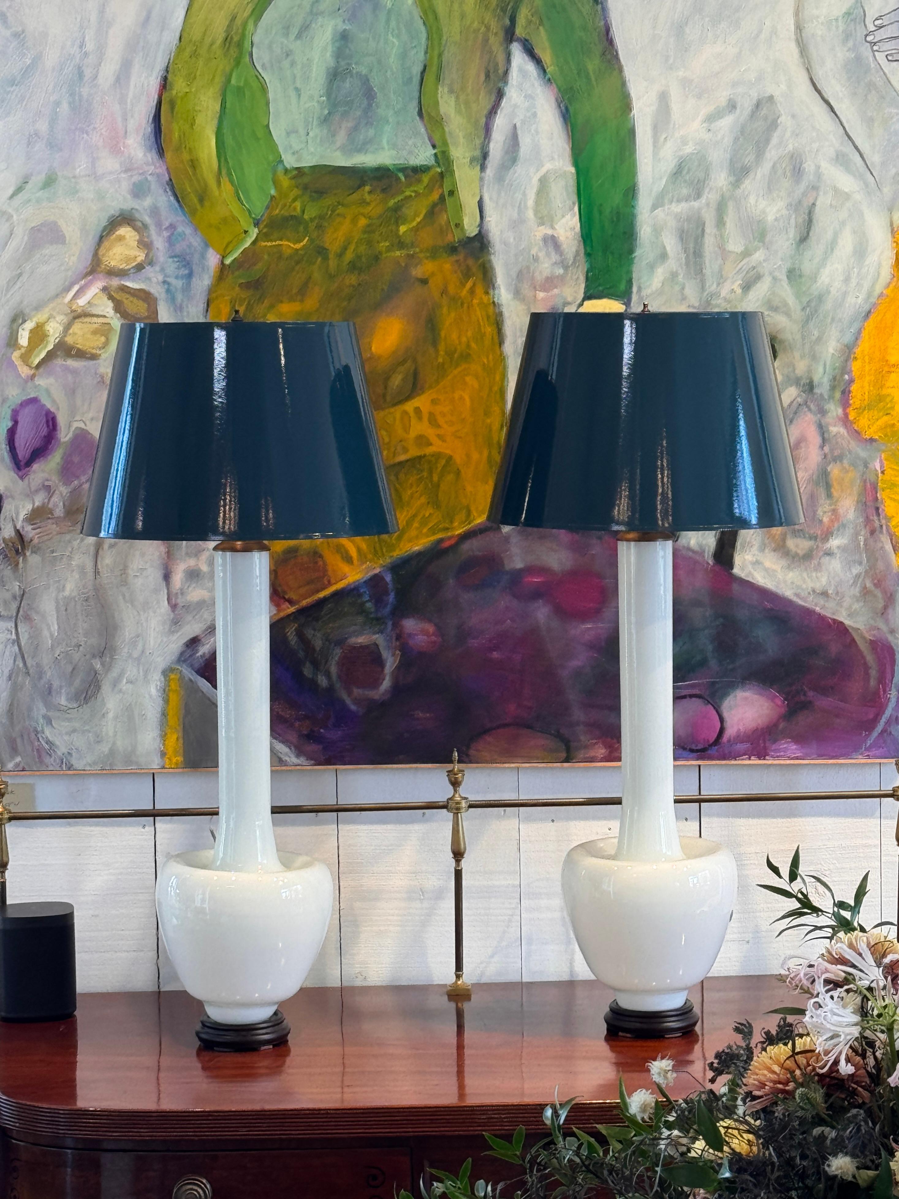 Pareja de lámparas de cristal de Murano, de vidrio blanco opaco liso, con elegantes cuellos alargados y bases redondeadas, colocadas sobre monturas circulares oscuras. El primer plano muestra la claridad y el tono uniforme del vidrio soplado a mano