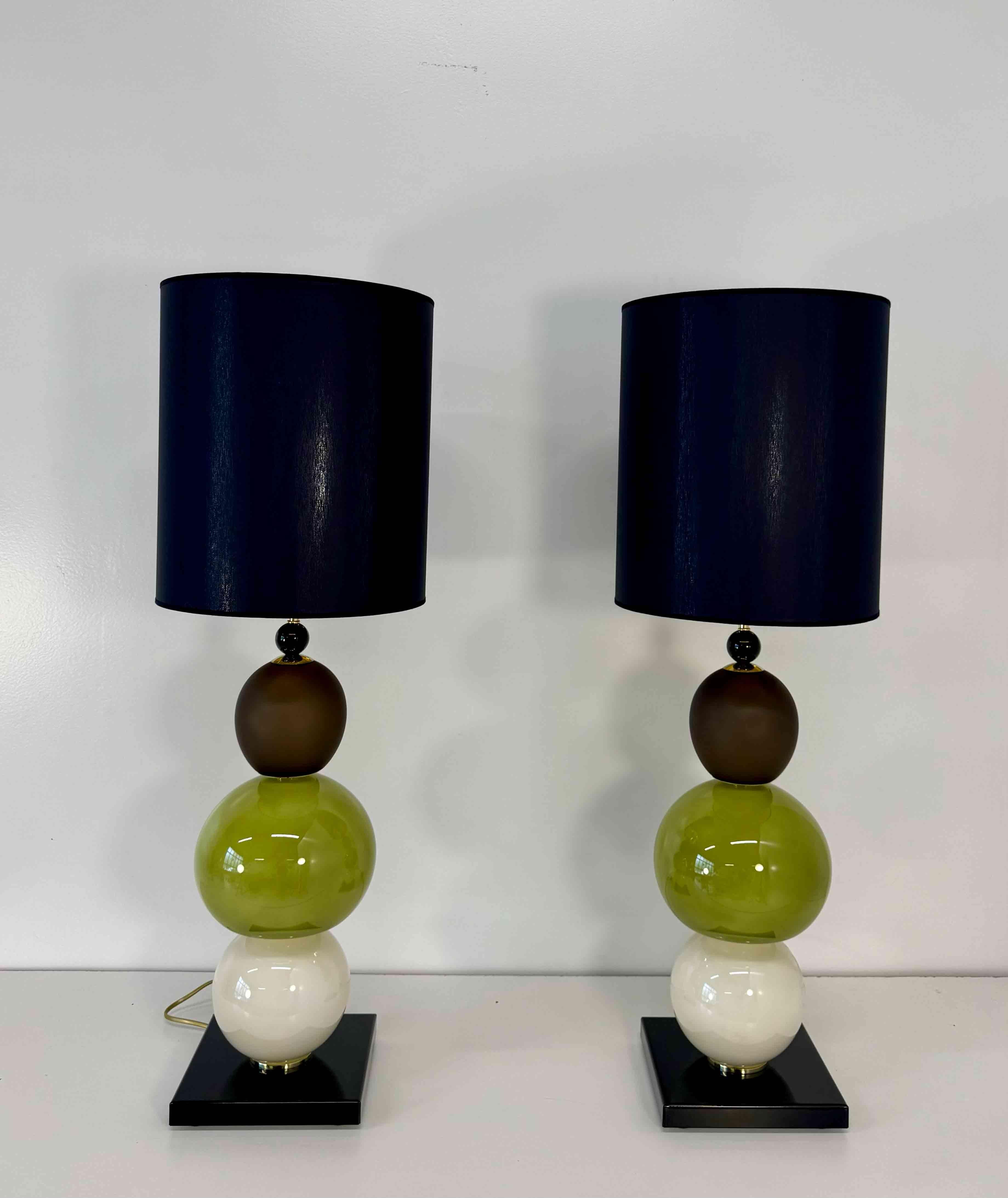 Elégante paire de lampes en verre de Murano fabriquées à la main en Italie dans les années 2000.
Chaque lampe comporte trois sphères en verre soufflé à la main - une en brun, une en vert et une en blanc perle - créant un jeu raffiné de couleurs et