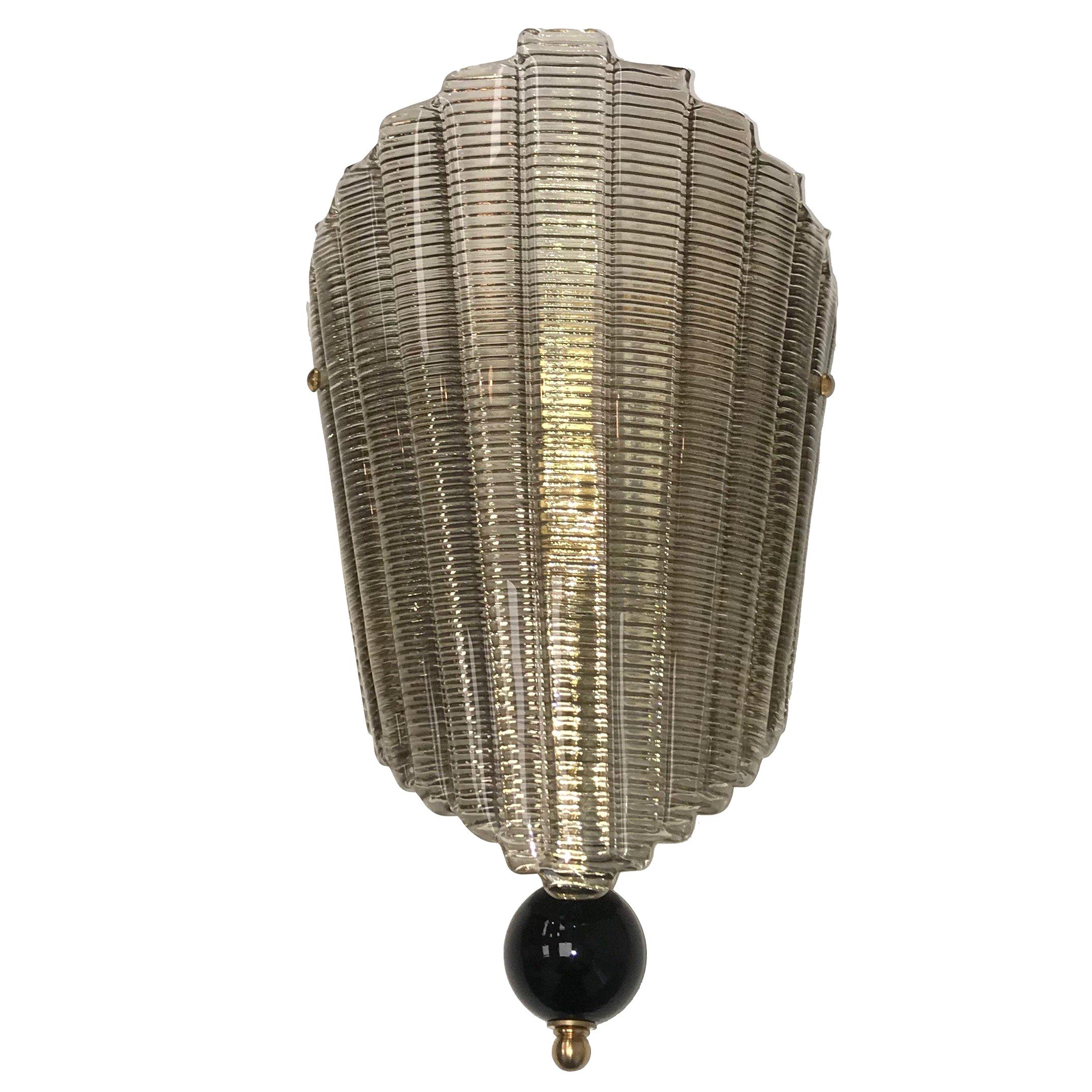 Fan-shaped Murano glass is simply attached via two brass screw fixings to the wall bracket to make this beautiful but effective Art Deco style sconce.
The glass has etchings that give the glass a gold appearance when the light reflects. This piece