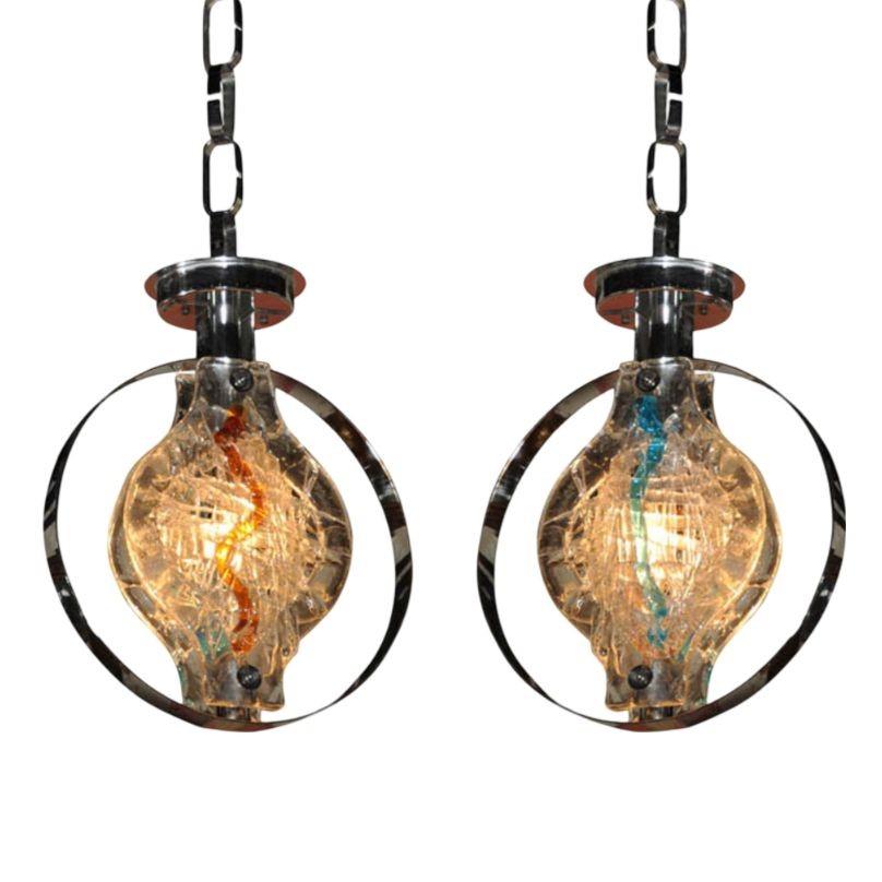 Pair of Mid-Century Murano glass pendant lights by Gino Vistosi, featuring textured clear glass with vibrant internal swirls in blue and amber. Suspended in sculptural chrome rings, these striking fixtures blend Space Age design with Italian