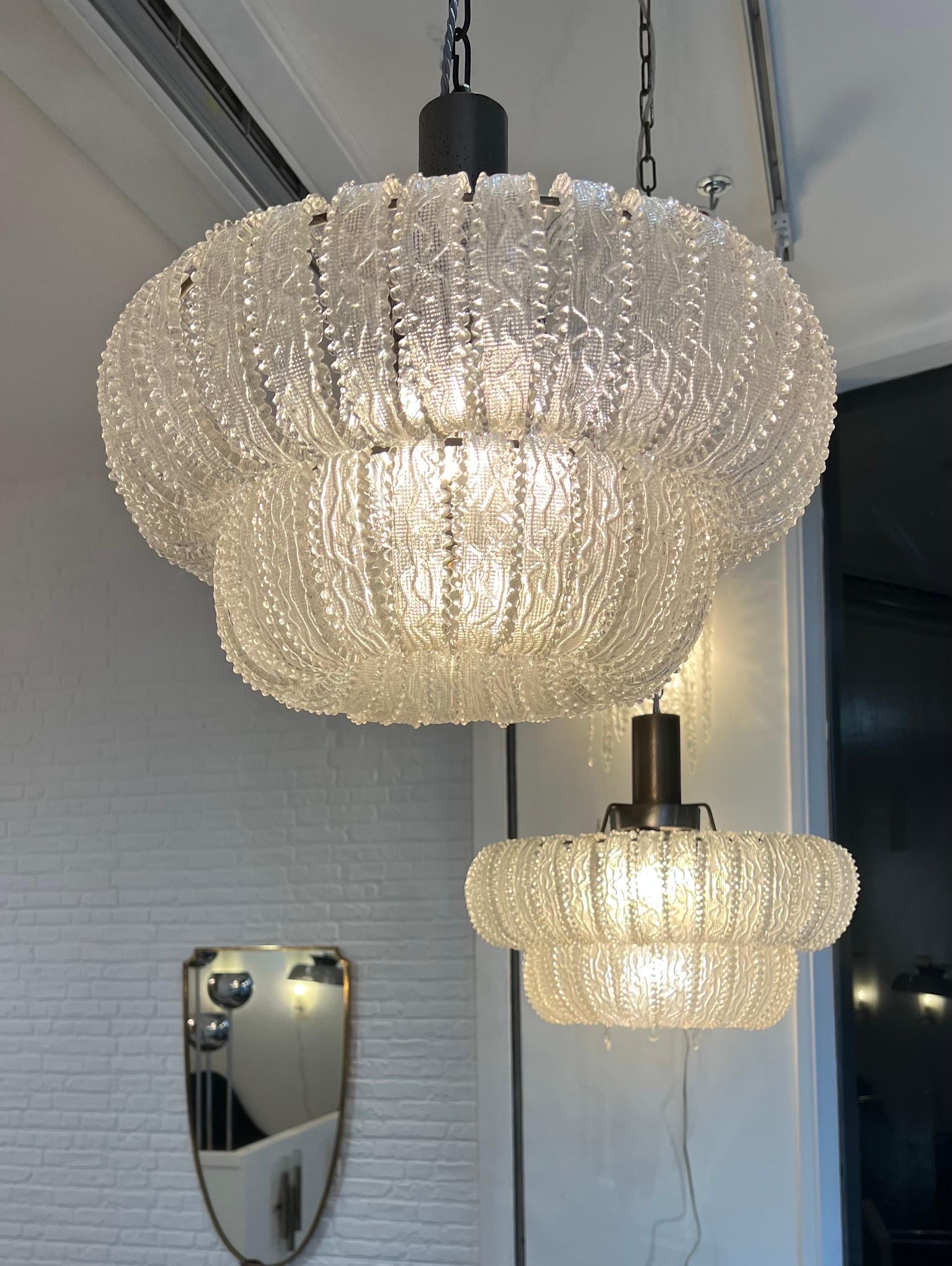 A fine pair of two tier Murano glass pendants with twisted leaves supported by nickel plated metal structure. 
Each pendant has 4 bulb holders . 
Measurements without the chains Height 40cm .. upper tier diameter 45cm and lower tier diameter 30cm