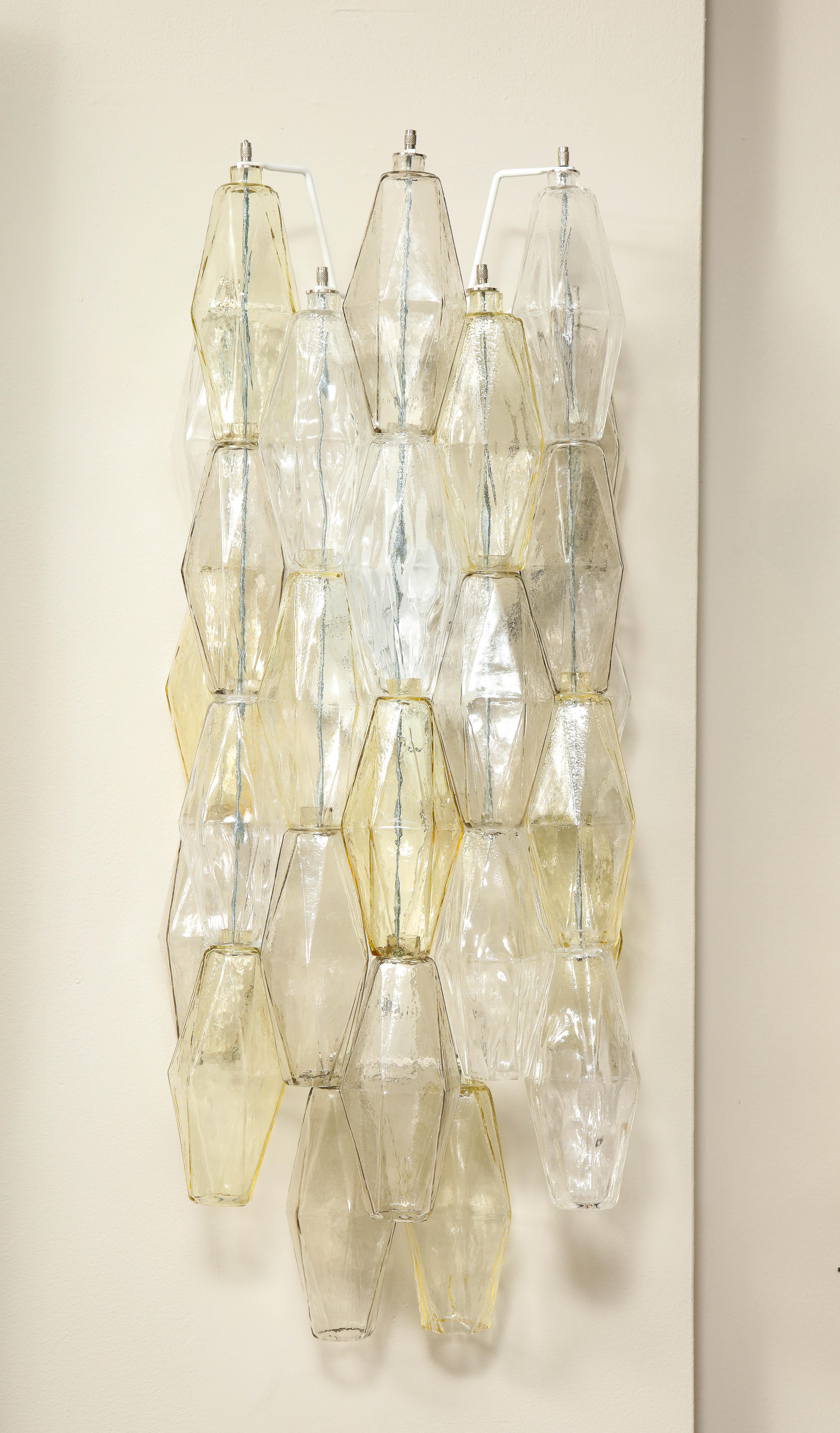 Applique a poliedro in vetro di Murano trasparente, fumé e ambra, realizzate a mano. Ciascuna con tre prese a candelabro e cornice bianca Italia, 2021.

È possibile personalizzare le dimensioni e il colore del vetro.