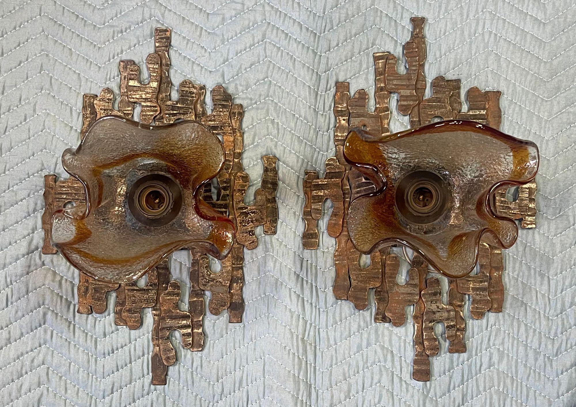 Striking pair of Rare Italian sconces designed by Mazzega in the 1970's, featuring hand-blown clear and amber Murano glass shades. The organic forms are mounted on bold Brutalist-style metal frames with a rich aged patina, adding texture and depth.