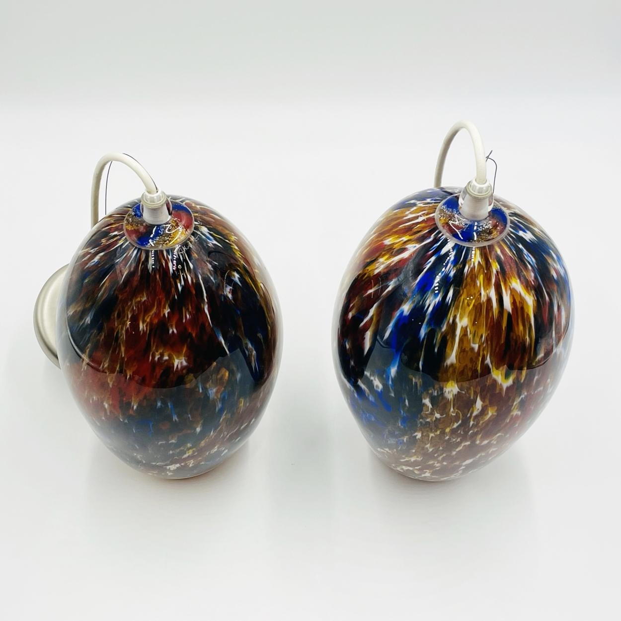 Beautiful pair of Murano glass style art glass pendant lights signed and dated 2012.

The pieces are very colorful and vibrant, they have a beautiful ovoid shape.

Measurements:
Smaller pendant:
Glass body only 13 high x 26.50 high to top of