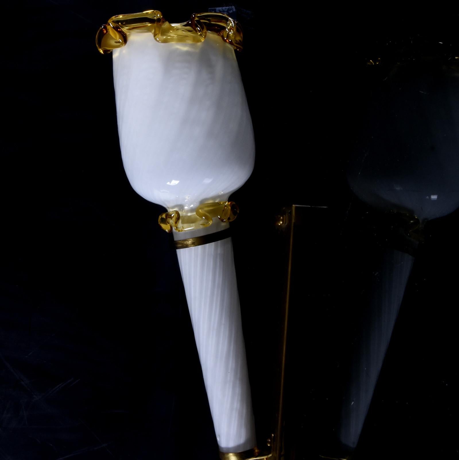 Pareja de apliques antorcha de cristal de Murano fabricados en Italia en la década de 1970. Lámpara de pared de cristal blanco arremolinado con decoración de cristal amarillo transparente.
El aplique está montado sobre un soporte de latón.
Las
