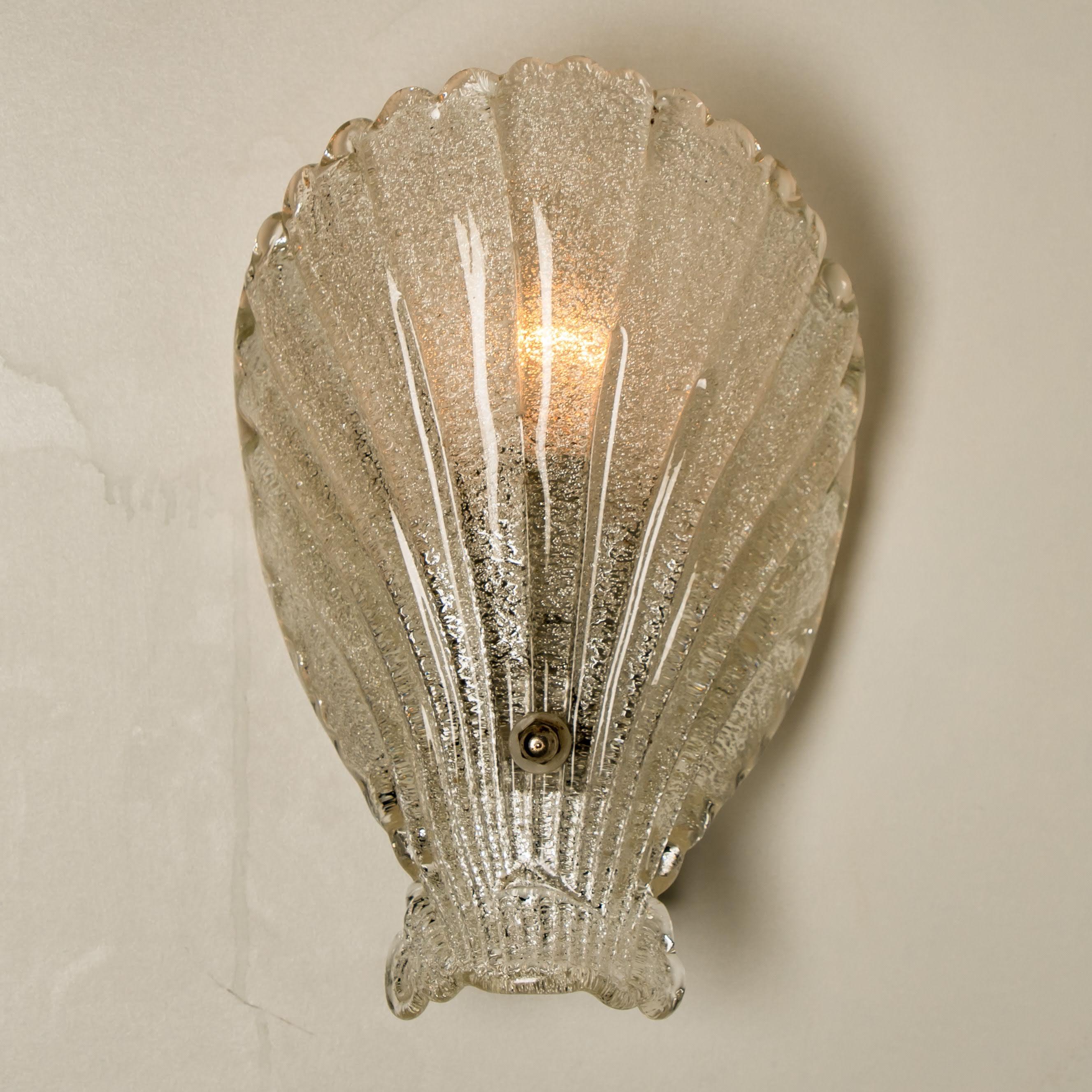 Pair of sea shell form wall lights, produced in Italy, in textured glass, affixed against a chrome base, circa 1960s.
An iconic design from the 1960s and still relevant today.

Good condition, consistent with age and use. Each light requires one