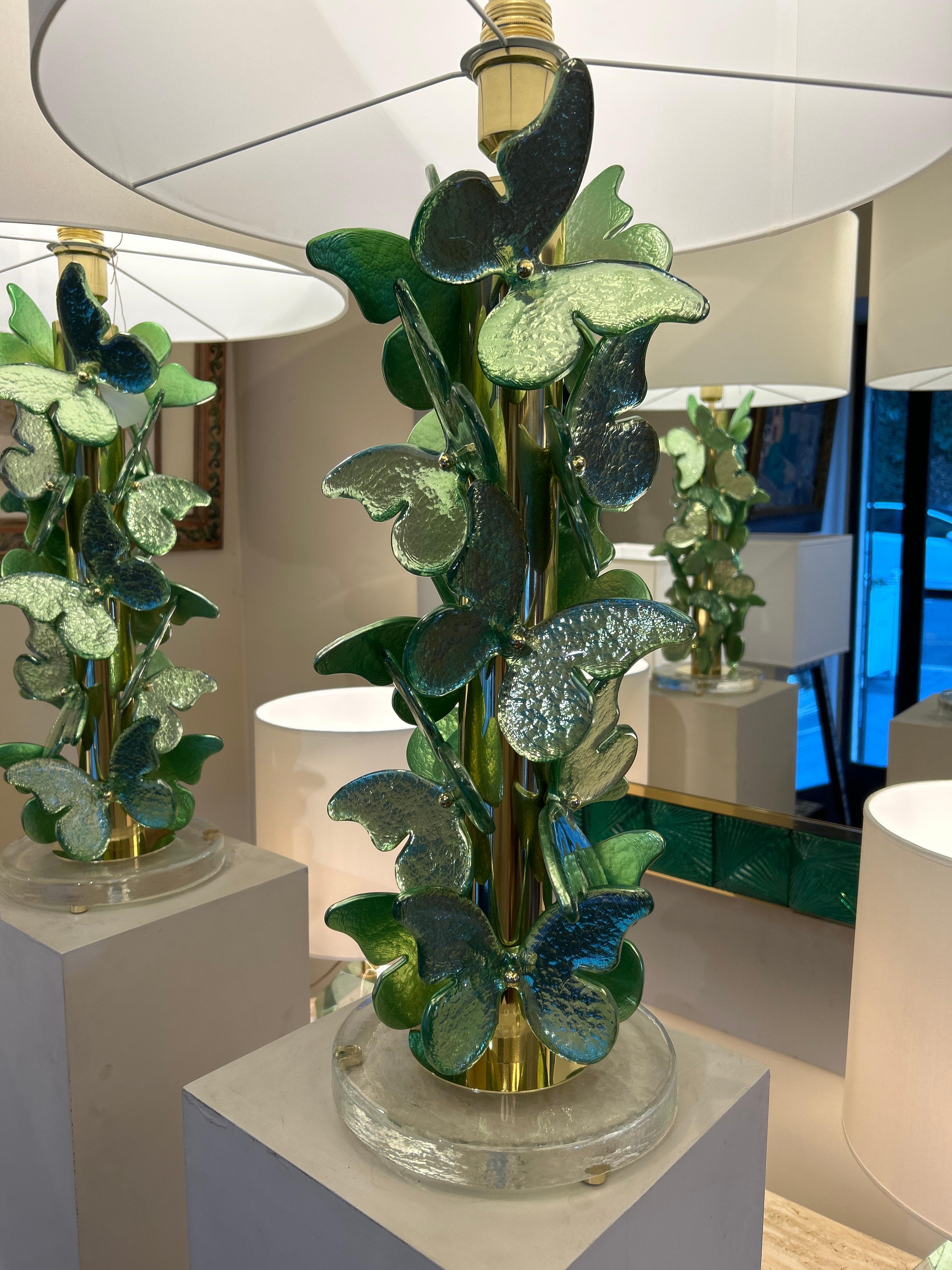 La pareja de lámparas de Murano son elegantes piezas decorativas de estilo botánico y sofisticado. Se apoya en una base circular de cristal transparente, que le confiere un efecto de ligereza y modernidad. La base de la lámpara está decorada con un