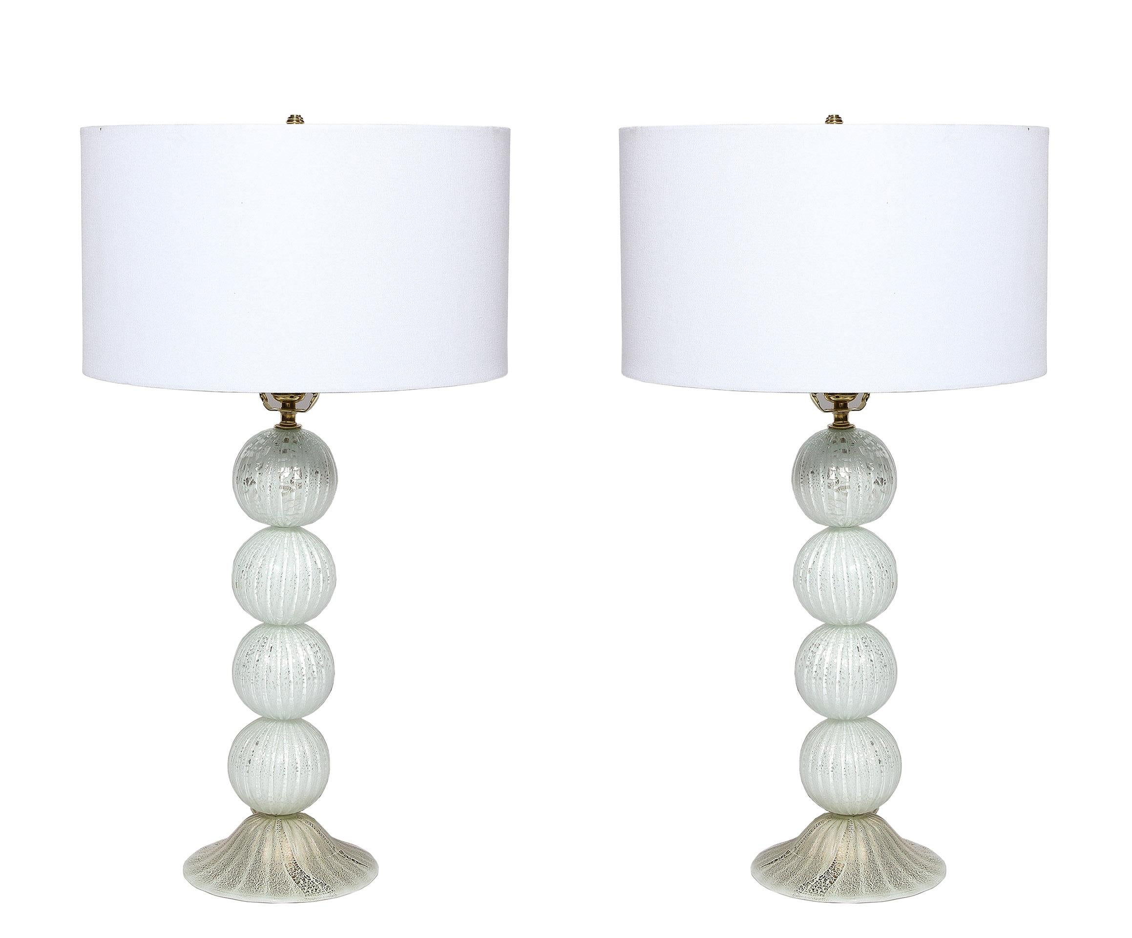 The pair of lamps comprised of stacked white and gilt handblown spheres on a conic base. 
They are newly wired to US standards.