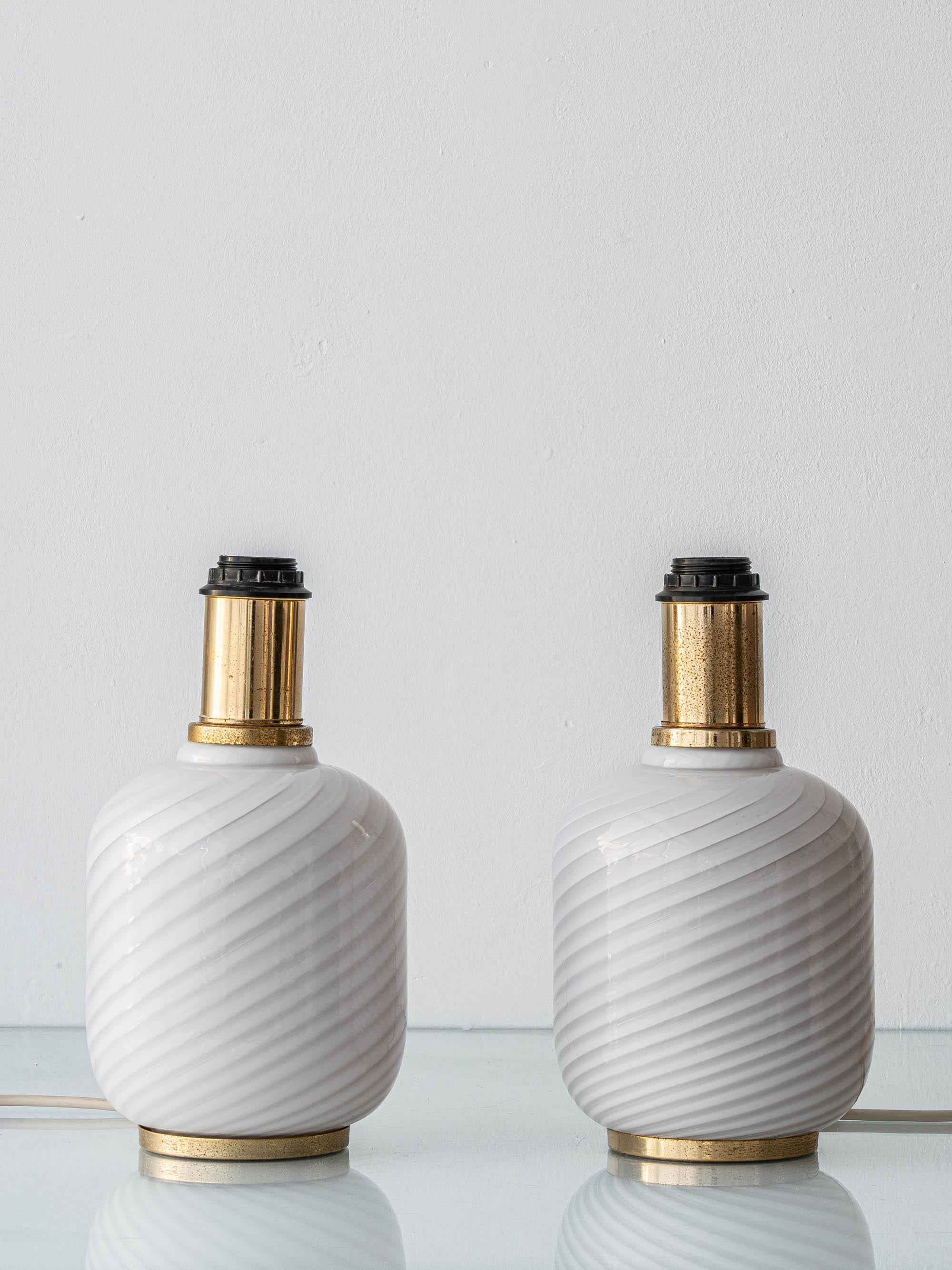 A matched pair of Murano glass table lamps by Vetri, Italy, dating from the 1970s. Each lamp is hand-blown in cased white opaline lattimo glass with a continuous twisted spiral pattern that gives a striking presence when unlit and a warm, diffused