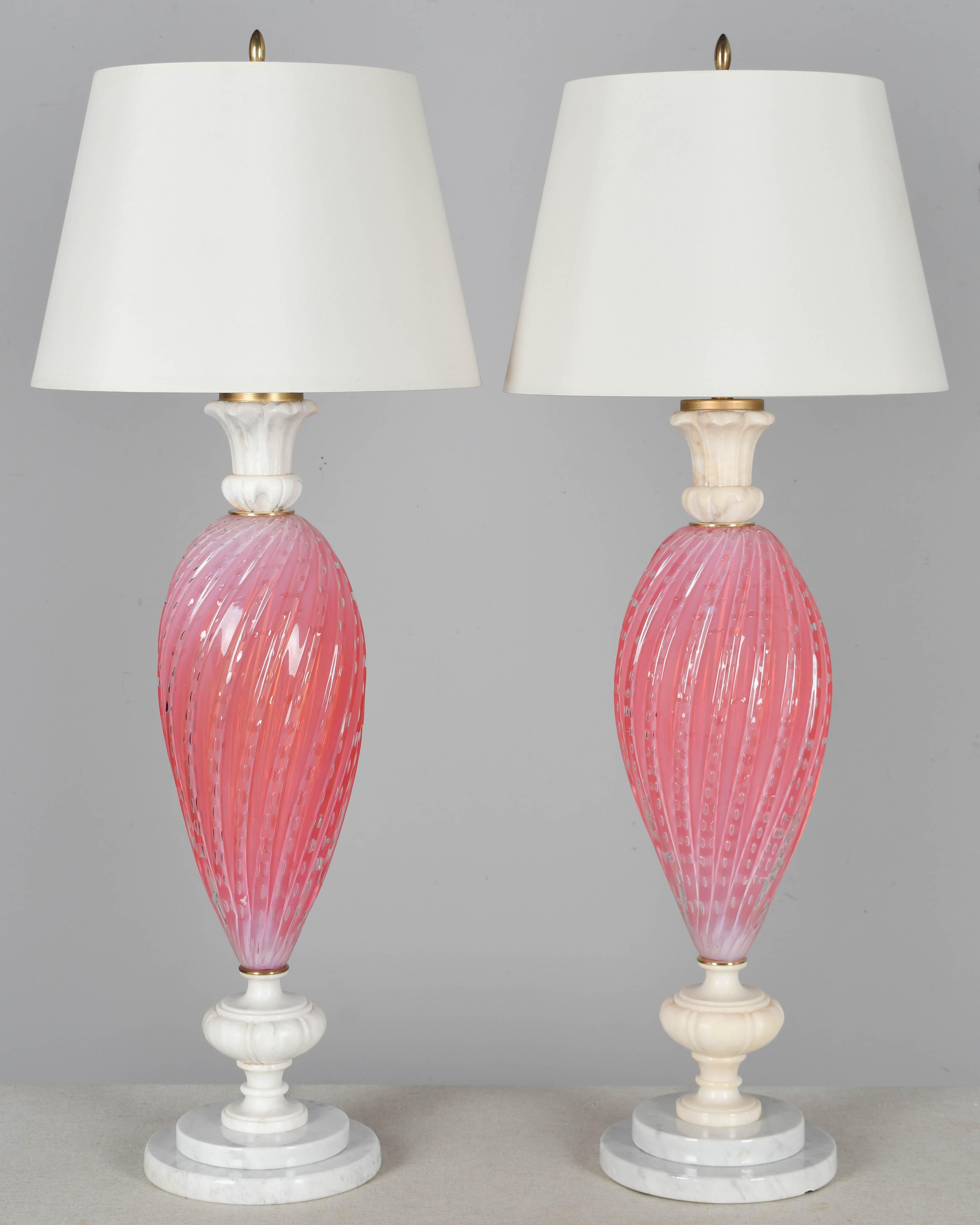 A pair of Mid Century Murano glass lamps by Alfredo Barbini. Beautiful opalescent cotton candy pink color. Hand-blown swirled ribbed glass with controlled bubbles. Original alabaster capital and stem and stacked marble bases, each lamp slightly