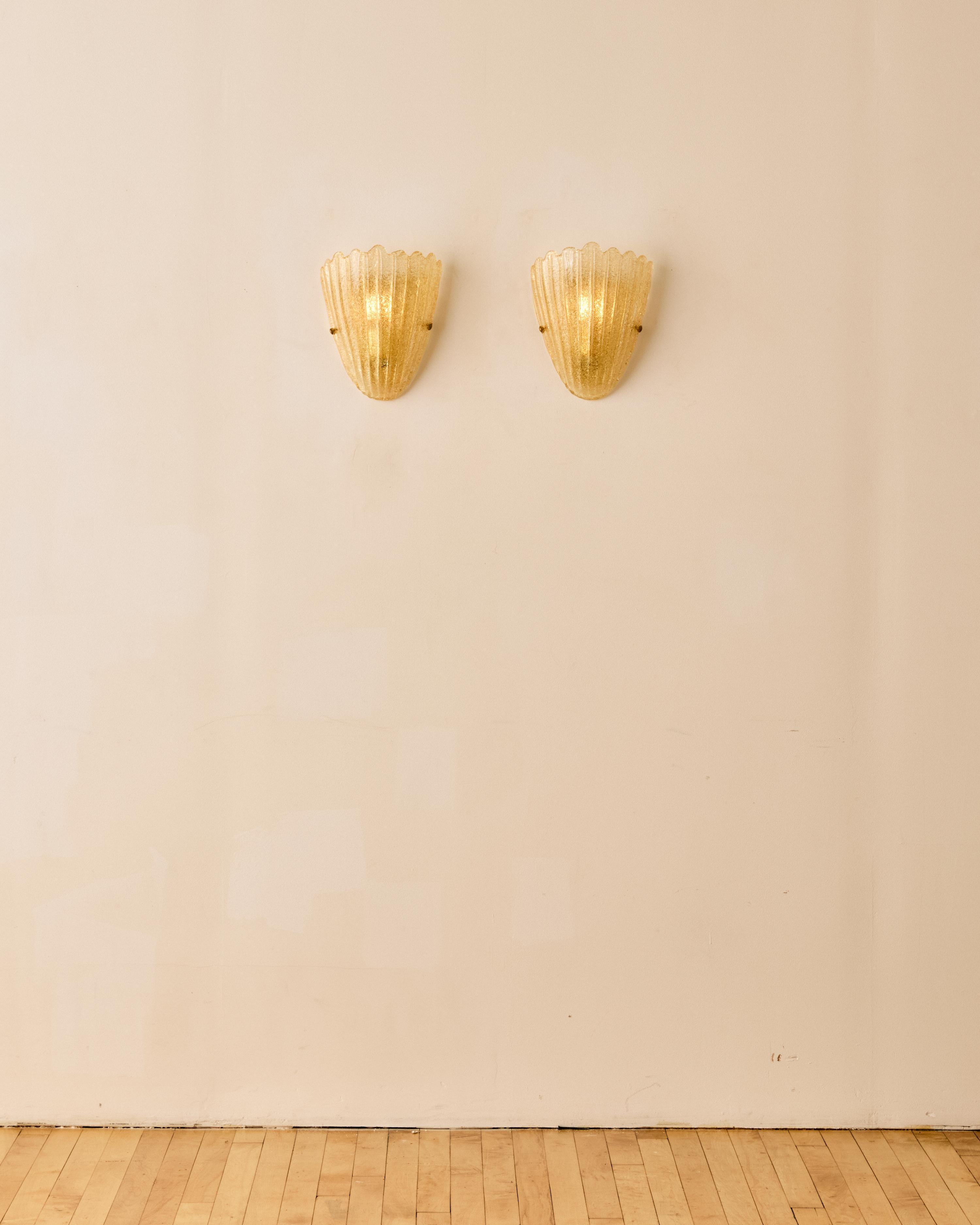 Pair of Murano glass shell wall sconces with gold flecks and brass detailing. 