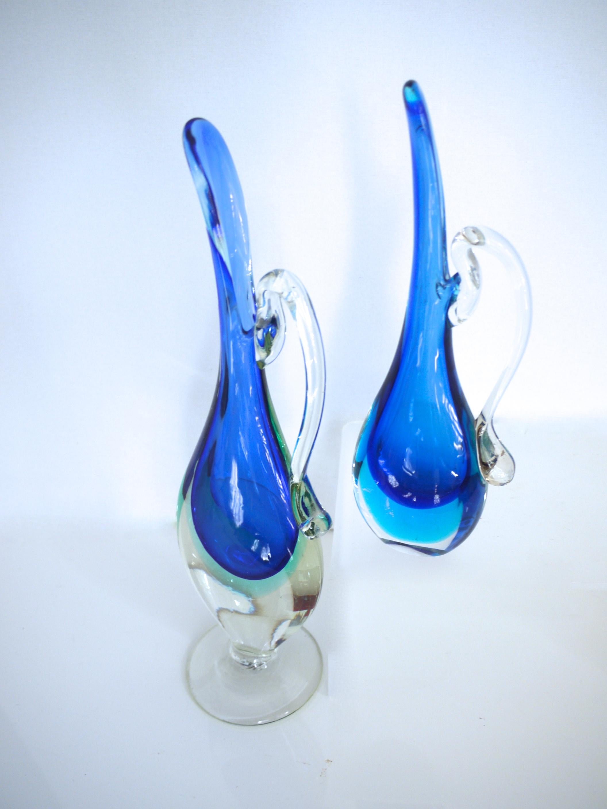 Pair of Murano Sommerso glass vases/pitcher in layered shades of blue.

Large Pitcher
Height 32 cms Depth 4.5 cms Width 10 cms
Weight 0.876 kgs

Small pitcher
Height 21 cms, width 5 cms, width at widest 7 cms
Weight 0.454 kgs.
