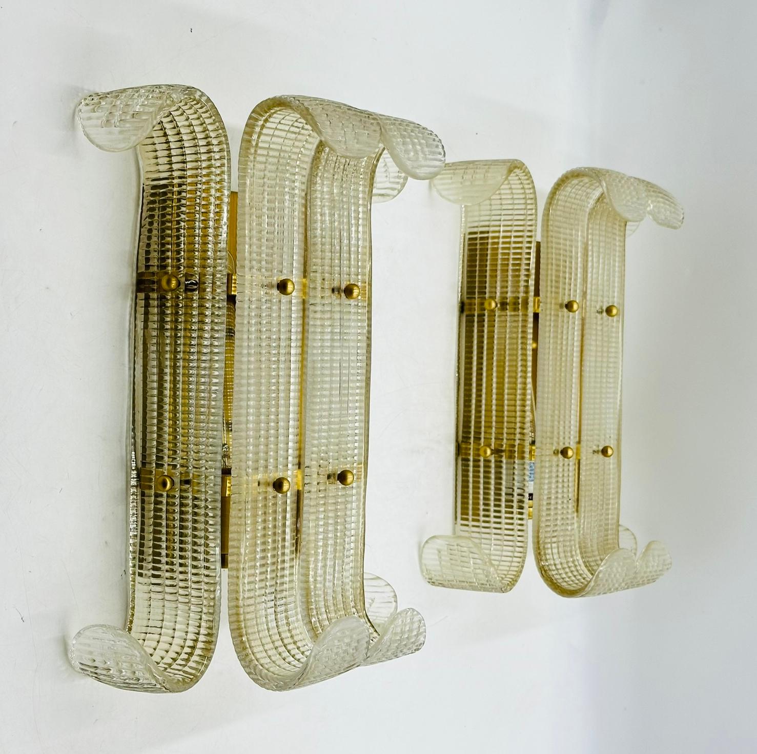 Paire d'appliques murales en laiton de style Murano.

Les appliques sont composées de pièces de verre semblables à des feuilles, fixées à un cadre en laiton et maintenues par des boules en laiton.

Les pièces ne sont pas marquées.
Mesures :
 15,50
