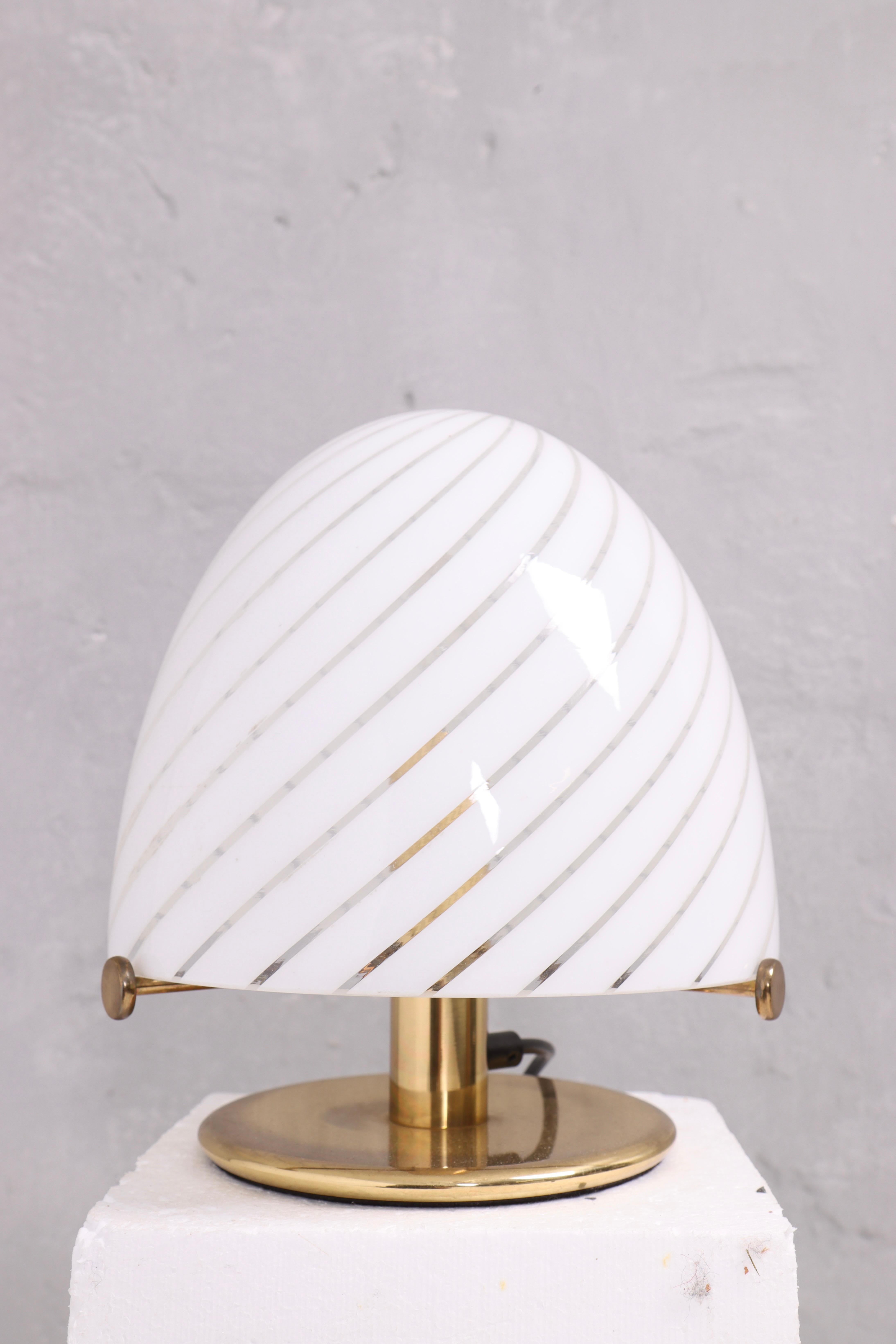 Precioso par de lámparas de sobremesa fabricadas en Murano, Italia, en la década de 1970. Las lámparas presentan pantallas de cristal soplado a mano en blanco con elegantes rayas en espiral, que crean un efecto de luz refinado y decorativo. Las