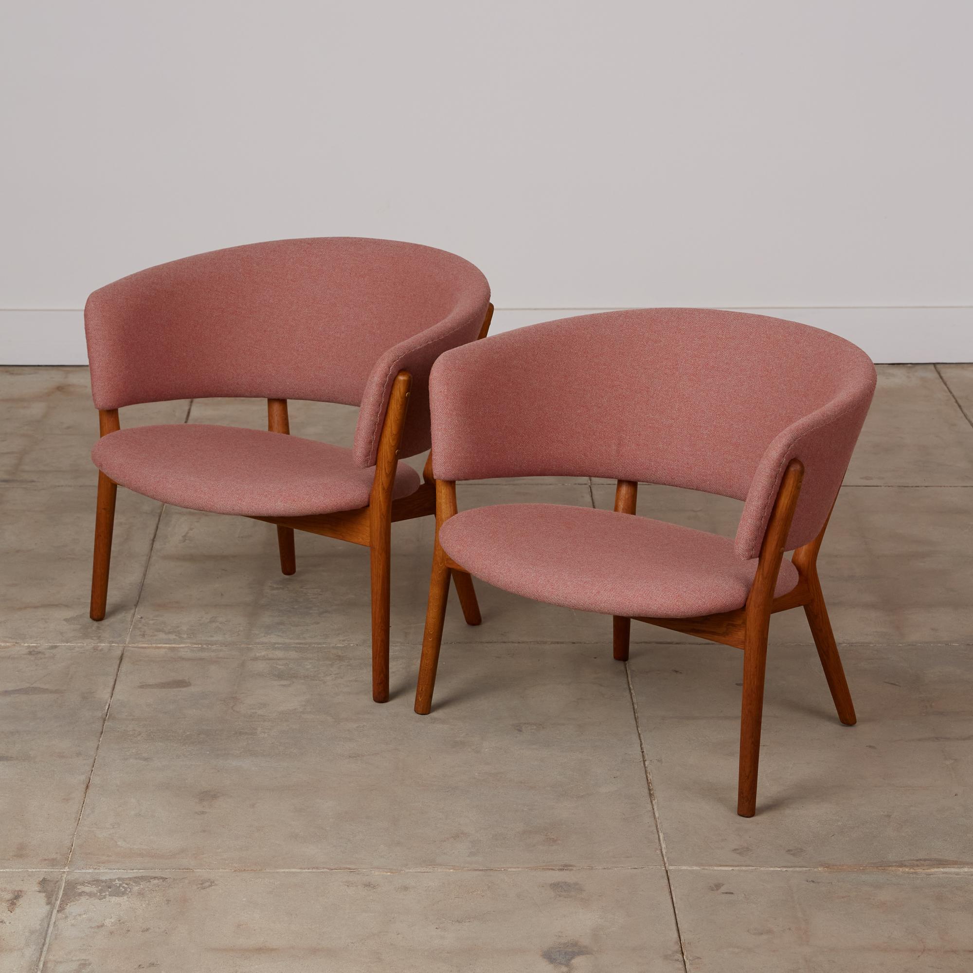Pair of Nanna Ditzel ND83 lounge chairs for Søren Willadsen, Denmark, c.1950s. These 1952-designed chairs by Ditzel feature oak frames and back supports that connect to the splayed legs. The seats and backs have the original salmon colored tweed