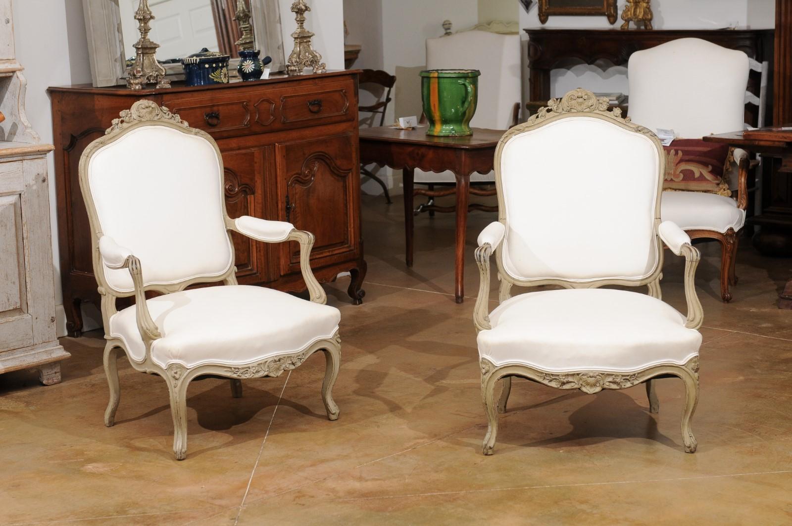 Paire de fauteuils en bois peint d'époque Napoléon III, datant du milieu du 19e siècle, à décor sculpté de fleurs et de feuillages. Créée en France au début du règne de l'empereur Napoléon III, cette paire de fauteuils présente un dos légèrement