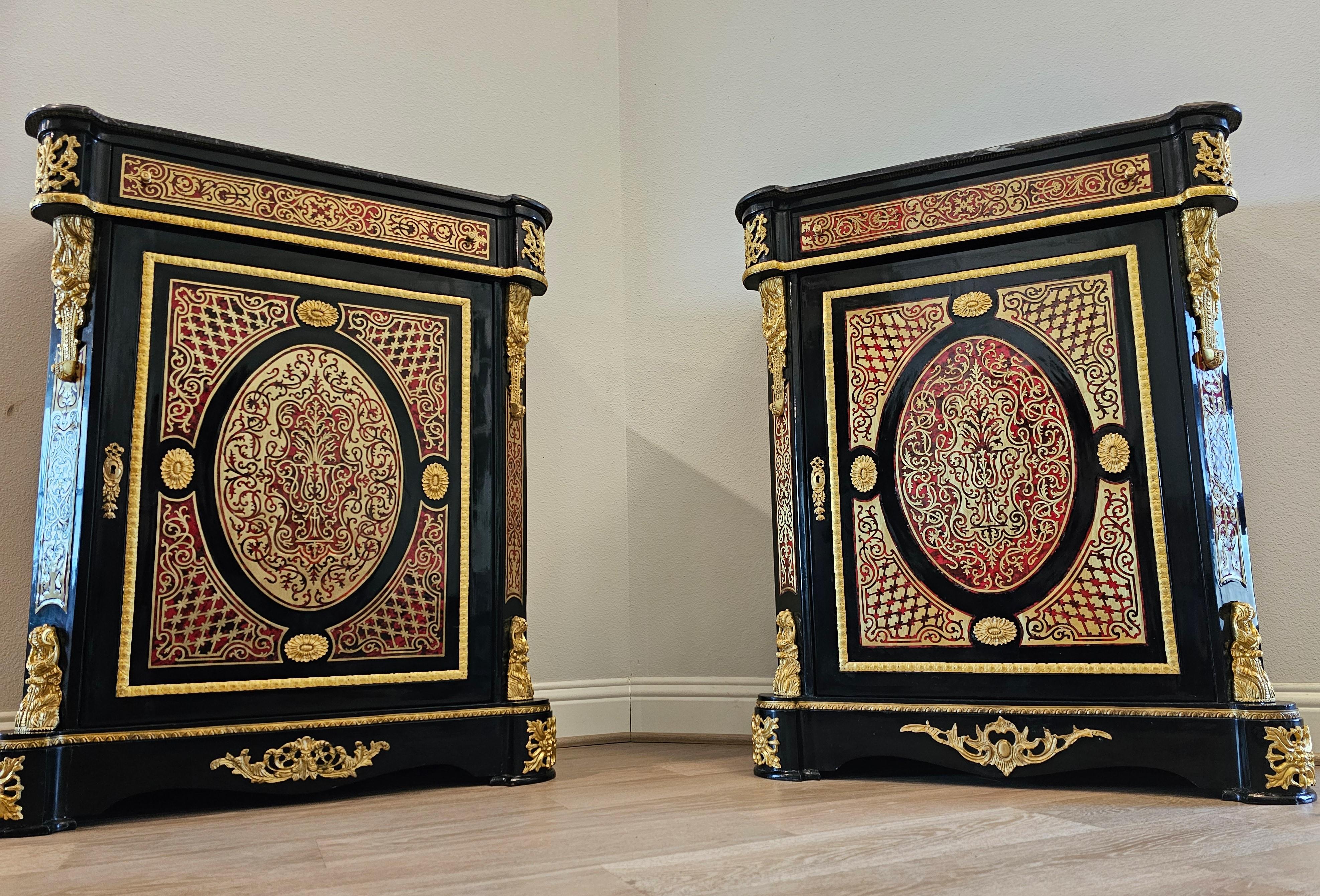 A pair of striking Napoleon III style ebonized cabinets, with Boulle style faux tortoiseshell cut-brass marquetry, gilt brass mounted black lacquered solid wood construction, topped with a shaped black marble top with white veining.

Mid-19th