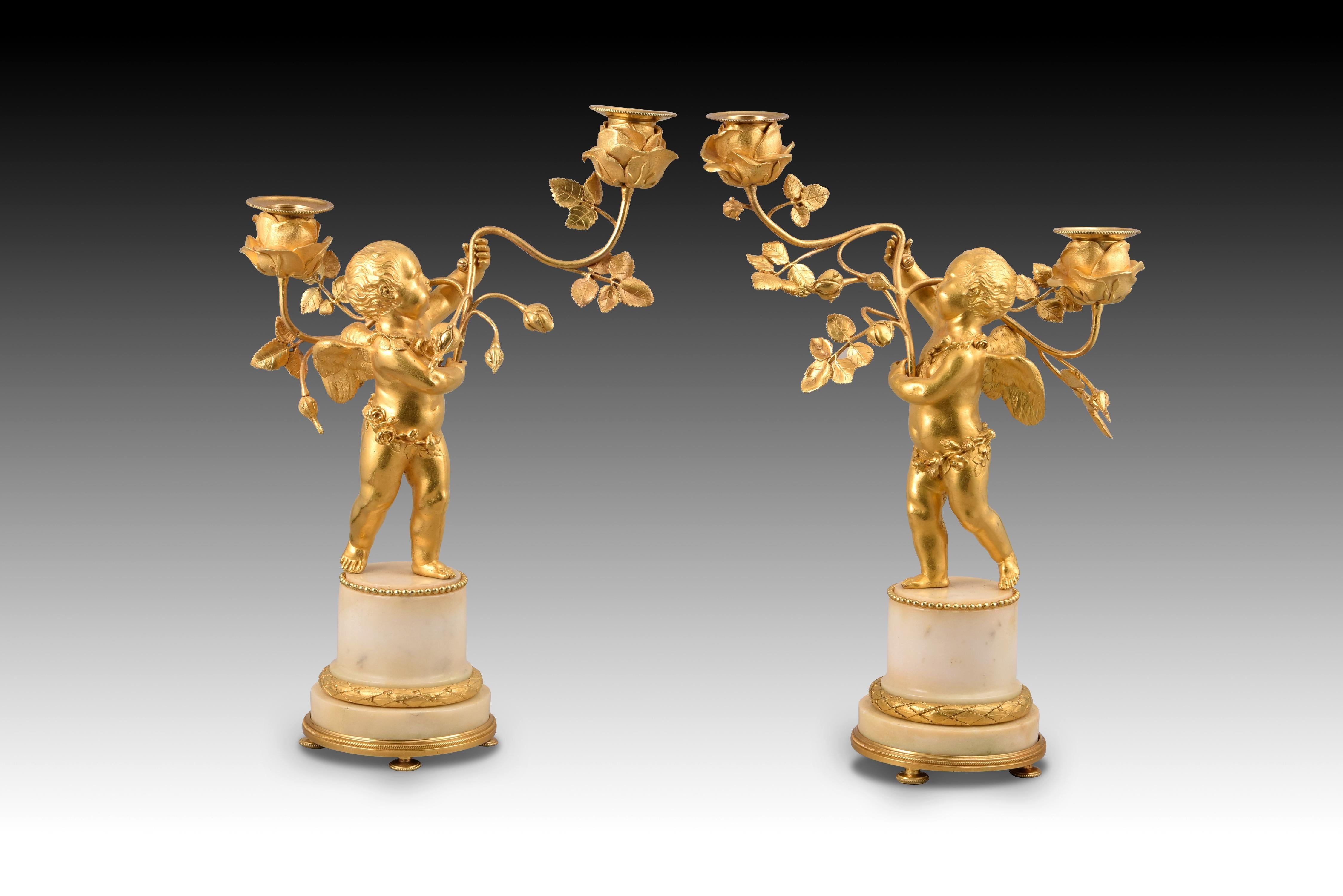 Pair of candlesticks. Gilt bronze, white marble. Around Napoleon III period, France. 
Pair of two-light chandeliers with a white marble base and gilt-bronze details made in gilt-bronze that each show a halfnaked Cupid or little angel with its body