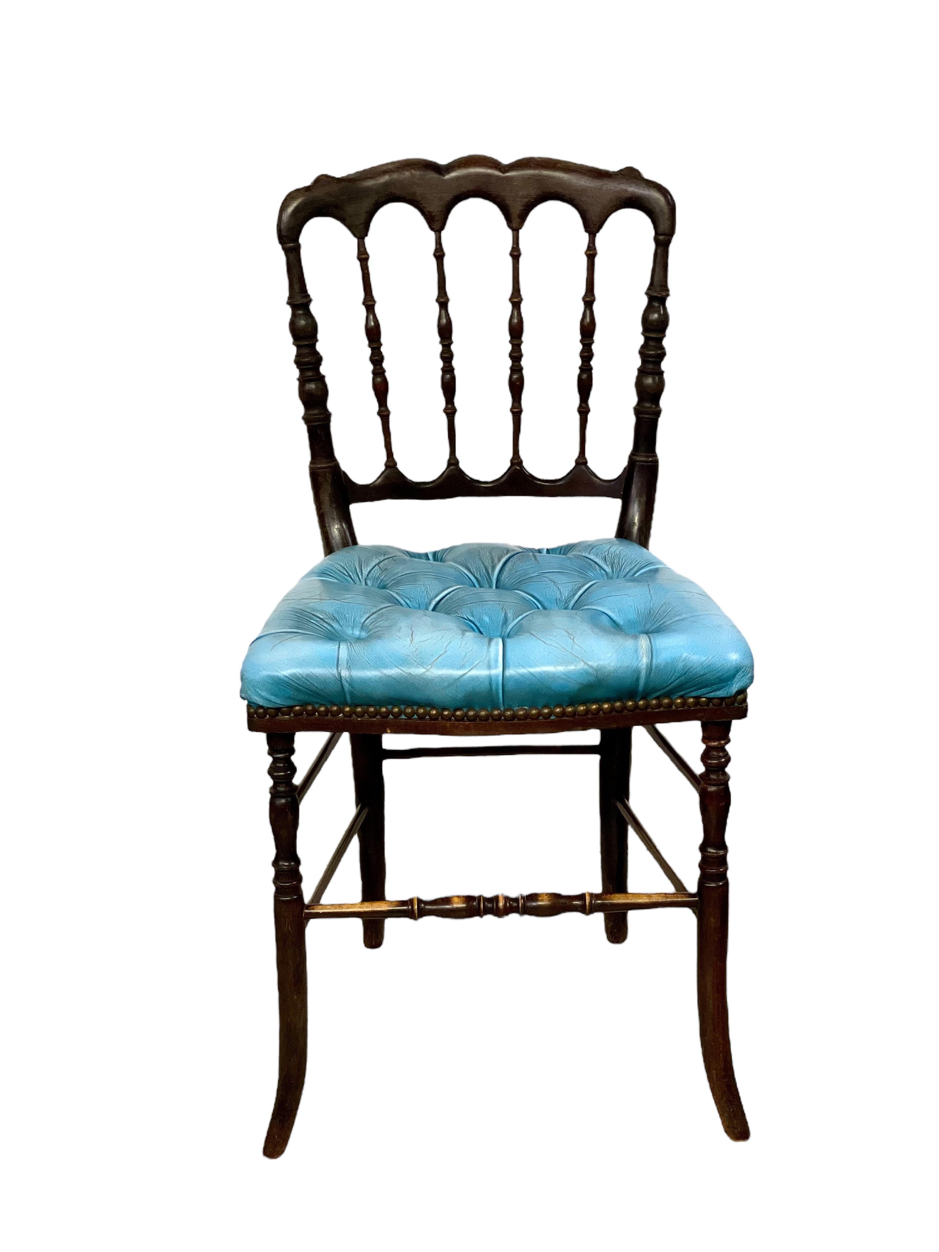 A fabulous pair of 19th century Napoleon III carved wooden side chairs, each with a delicate spindle back and ornately shaped top rail. The seats are plush and comfortable, resplendent in buttoned blue leather and neatly secured all round with a