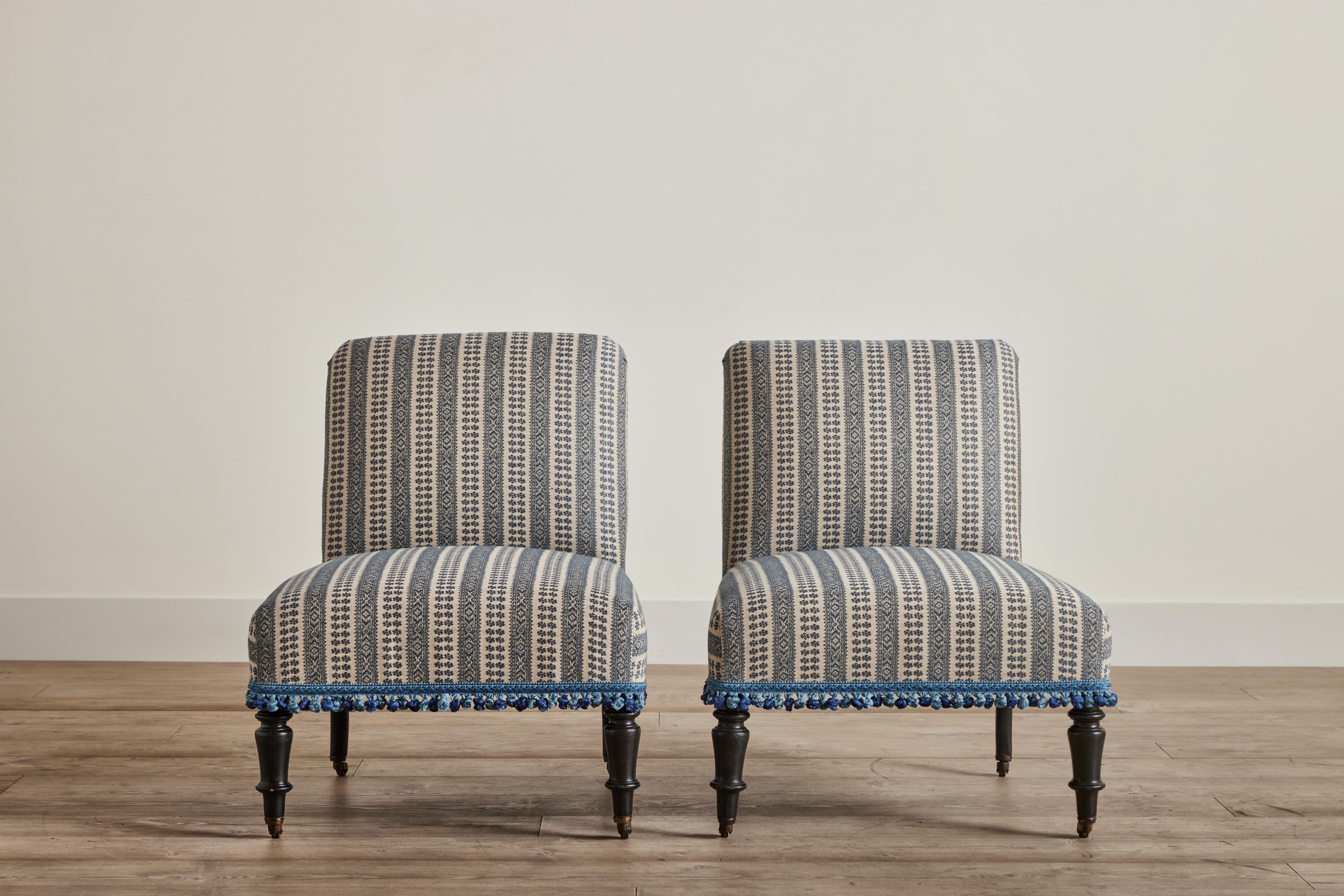 Pair of Napoleon III slipper chairs from France circa 1880. This pair has been newly upholstered in Susan Deliss fabric “Patmos” weave in Smokey Blue with vintage Italian tassel trim. Some wear on original wood legs that is consistent with age and