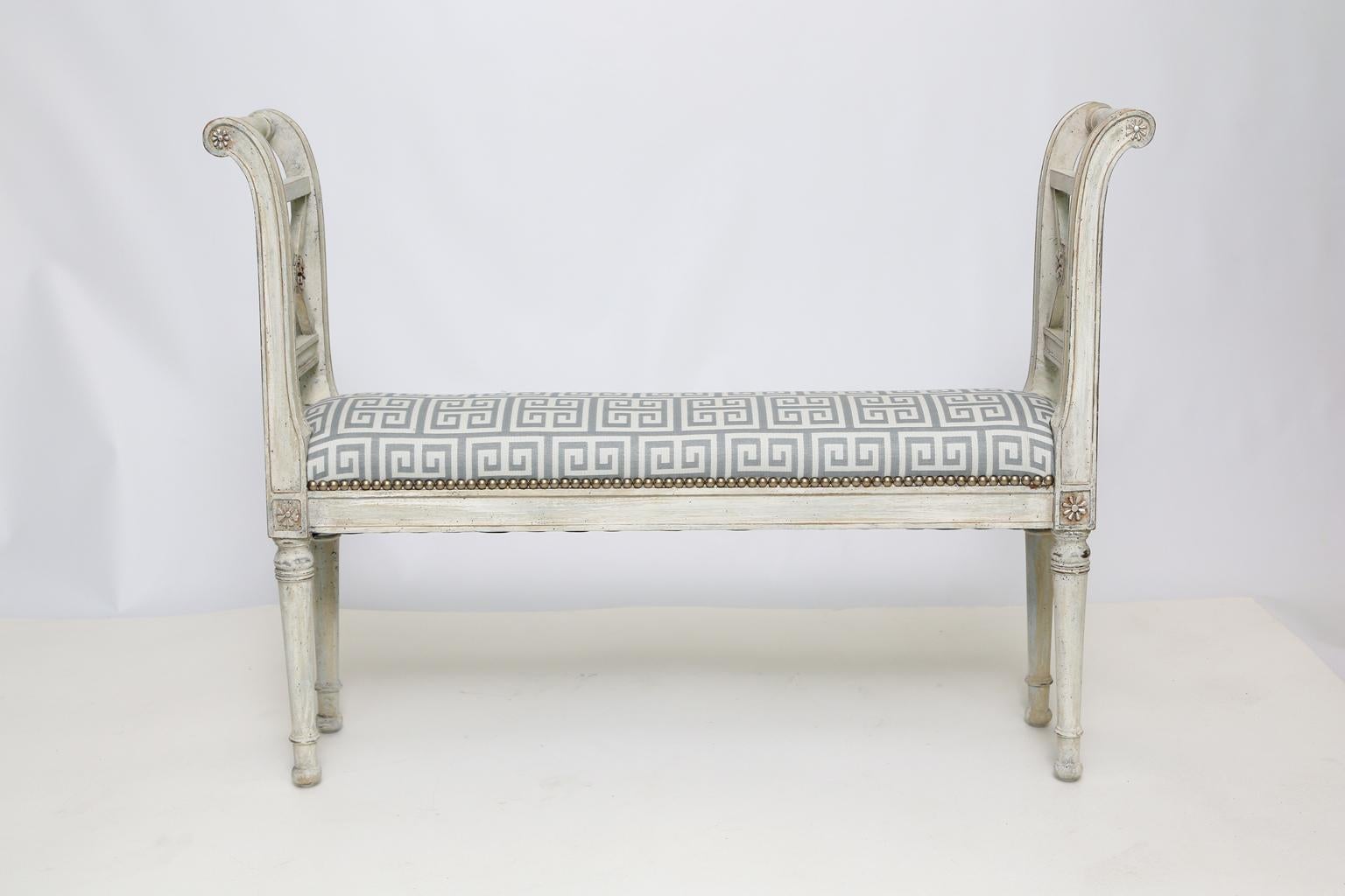 Benche, having narrow upholstered seat with silver nailheads, on a painted, fielded frame, with parcel silver gilt accents, showing desirable wear, with scrolled arms inset with X-frame, raised on round tapering legs, ending in toupie