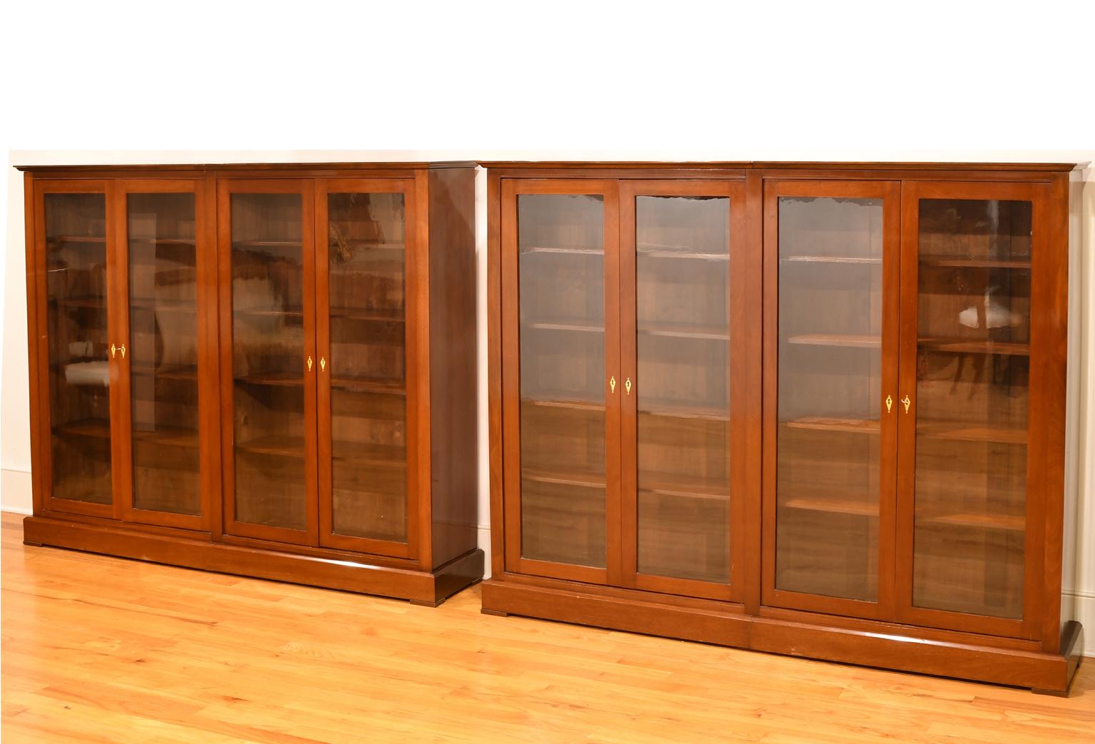 A handsome pair of Art Deco bookcases with sleek lines and understated refinement in fine mahogany with blown-glass panels that cover the length of each of the doors.  Each bookcase offers four cabinet doors with four shelves on each of two sides,