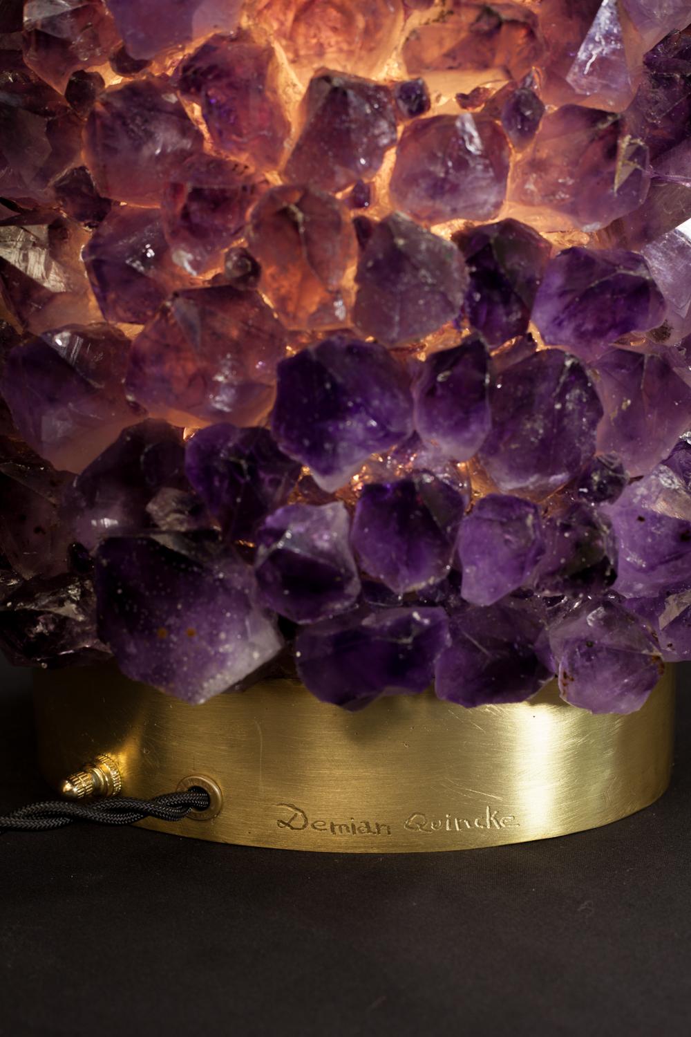 Pair of natural amethyst table lamps-signed by Demian Quincke
Aurea natural amethyst assembled and sculpted on casted oval brass base
Dimensions: 45 x 27 x 17 cm.

5W LED light
Bi-Volt 100-240V 38A and 8ft long black twisted 18 Gauge / SPT-2