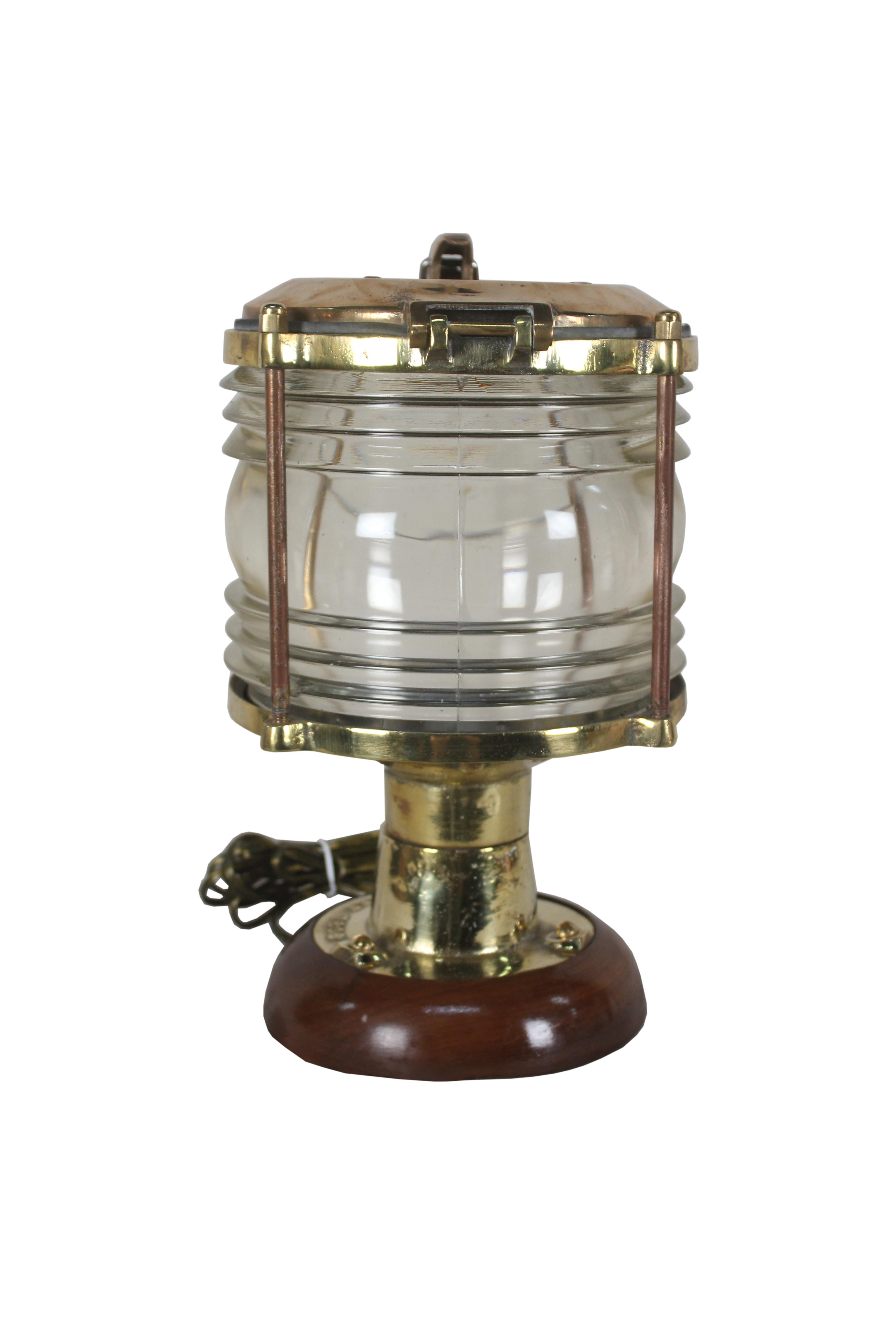 A pair of handsome brass ship's post lights with Fresnel Lens glass. These have been mounted on a teak base to use as table lamps. Rewired for American use and take a standard base light bulb. The brass top has a latch that lifts for access, 1970s,