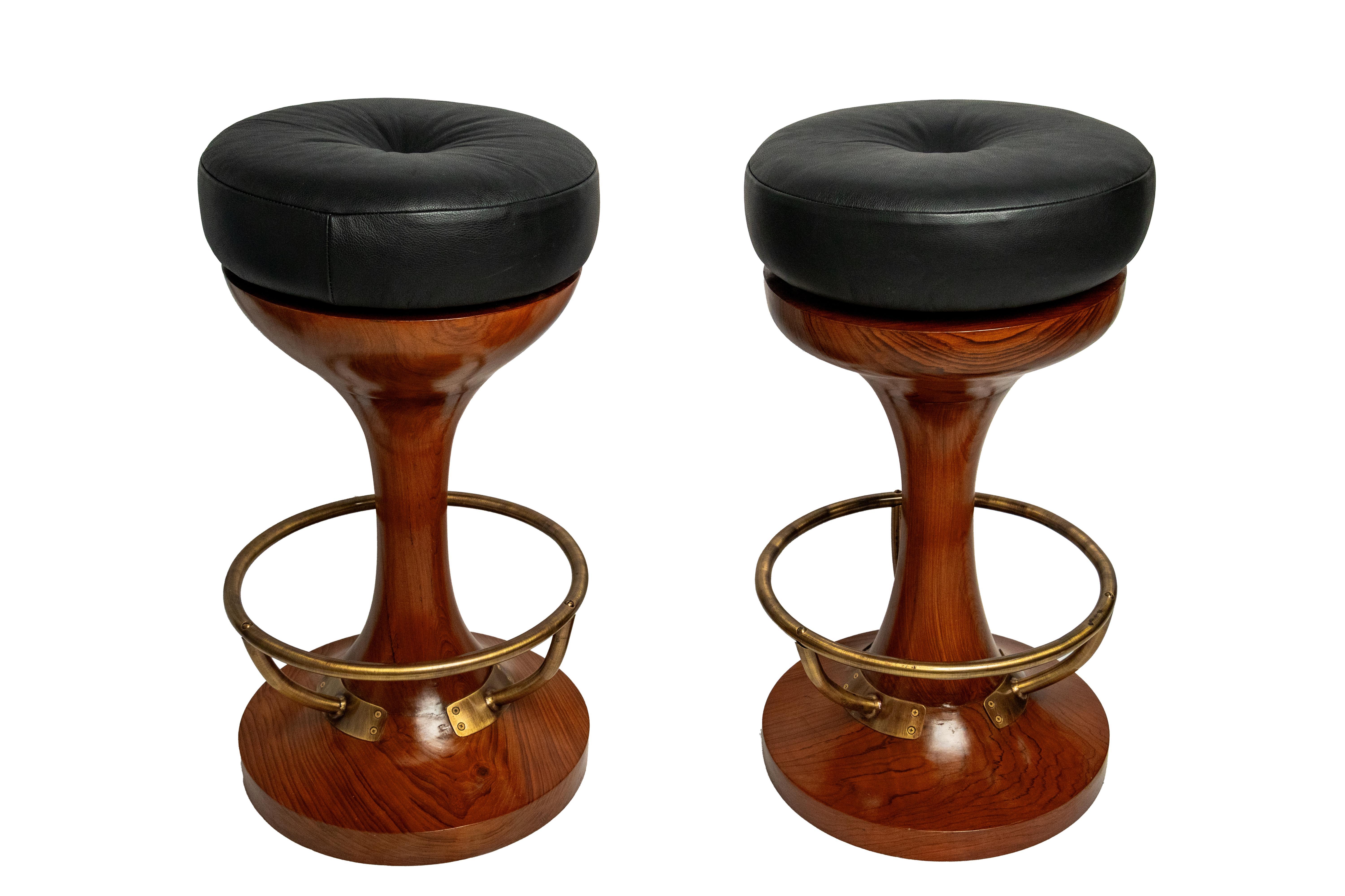 A handsome pair of solid teak bar stools from a decommissioned cruise ship.  They swivel and have a brass circular foot rail and a replaced leather seat.  Date to the 1970's and have been refinished.

The Lockhart Collection is a personally curated