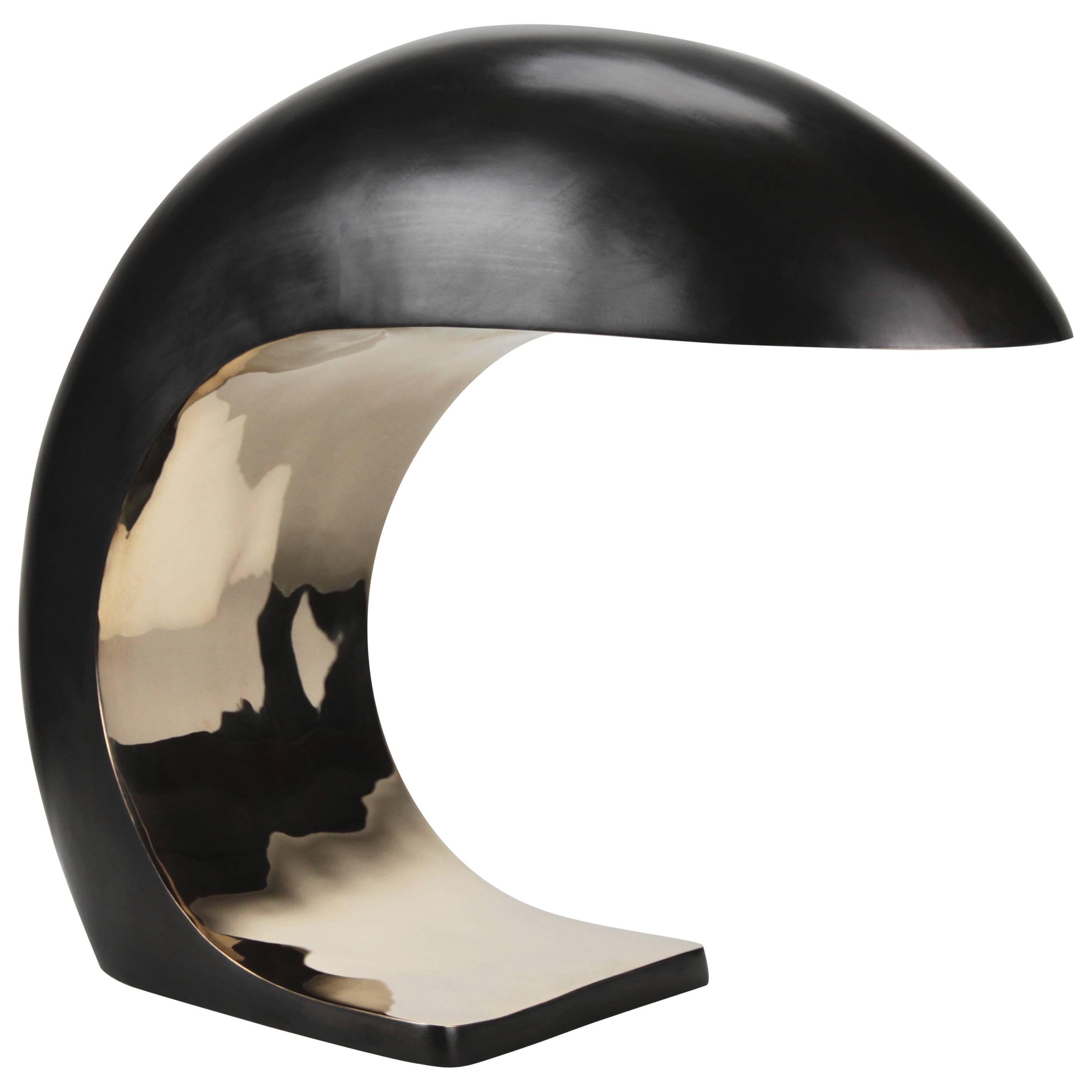 The Nautilus lamp in lamp is inspired by midcentury Italian design.
It is cast bronze and weighs up to 28 to 30 lbs. The outer shell has a blackened patina and the face is high polished to a mirrored finish and waxed.
 
The Nautilus illuminates