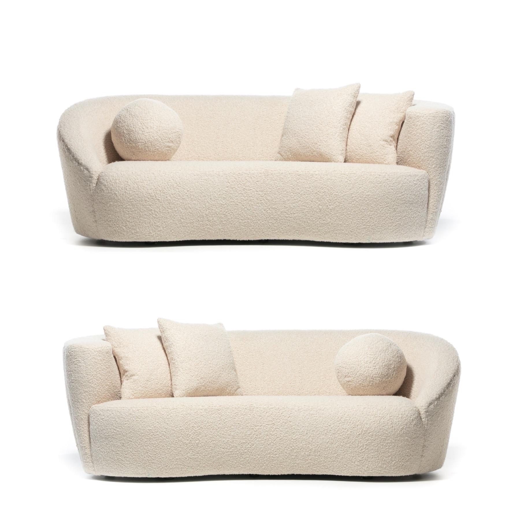 Mirroring pair of newly and professionally reupholstered Post Modern Nautilus sofas in ivory white bouclé by acclaimed designer Vladimir Kagan and made by Directional circa 1990. Known for his love of amorphous shapes and curves, each of these