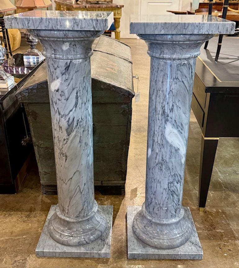 Le produit est une paire de piédestaux anciens en marbre de style néoclassique. Ces piédestaux sont conçus pour ajouter une touche d'élégance à tout cadre architectural ou de jardin. Le matériau marbre leur confère un aspect luxueux et intemporel,