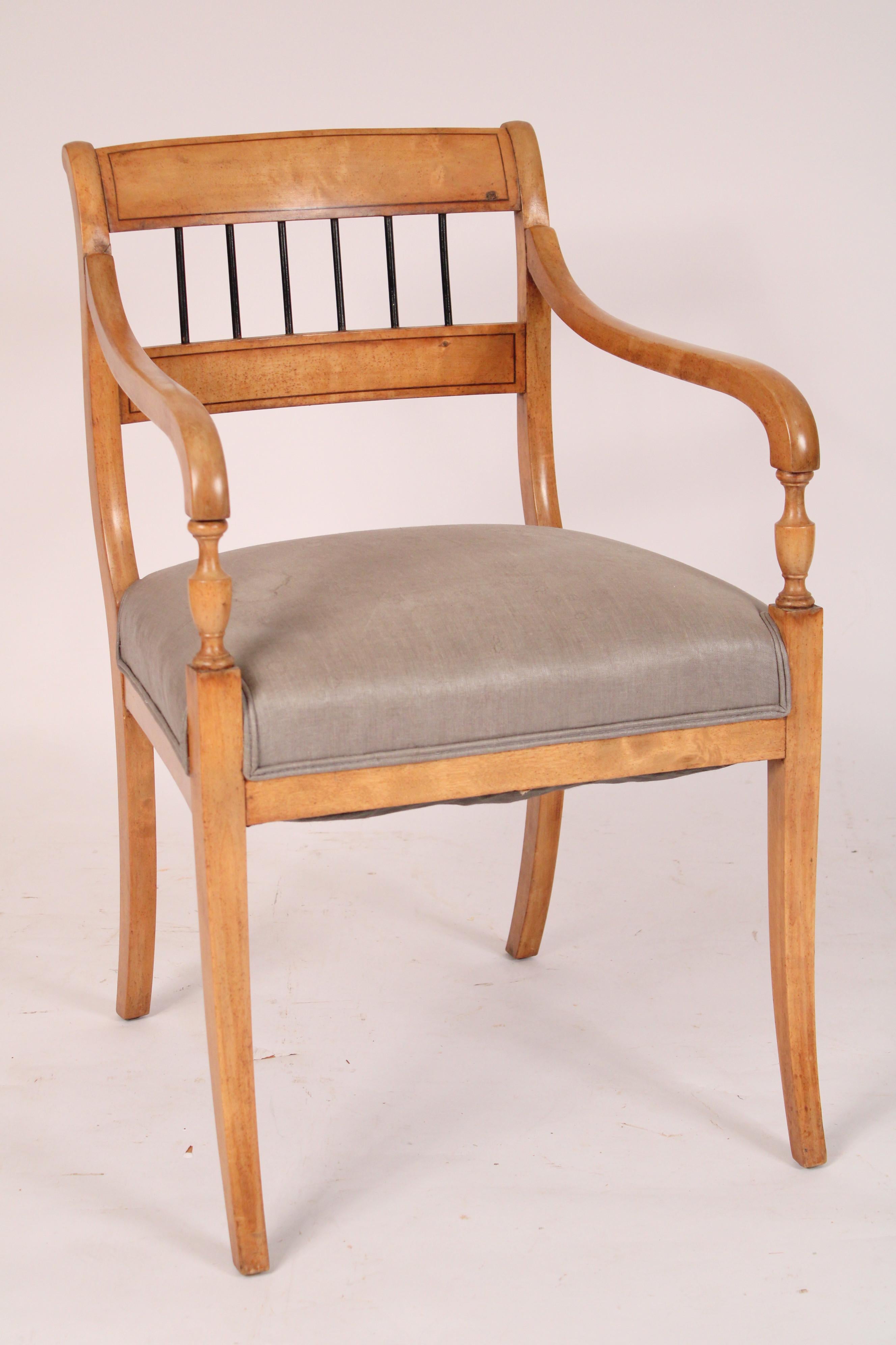 Paire de fauteuils en hêtre de style néoclassique, vers les années 1930. Le dossier est orné d'une traverse incisée en noir et de fuseaux ébonisés. L'assise est tapissée et les accoudoirs reposent sur des supports de bras en forme de vase et sur des