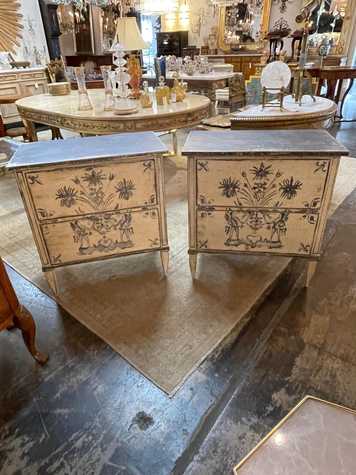 Lovely decorative pair of French Neo-Classical style hand painted bed side tables. Featuring interesting painted images including fleur- di- lis, flowers and angels in a dark blue. Beautiful patina as well. Fabulous!!