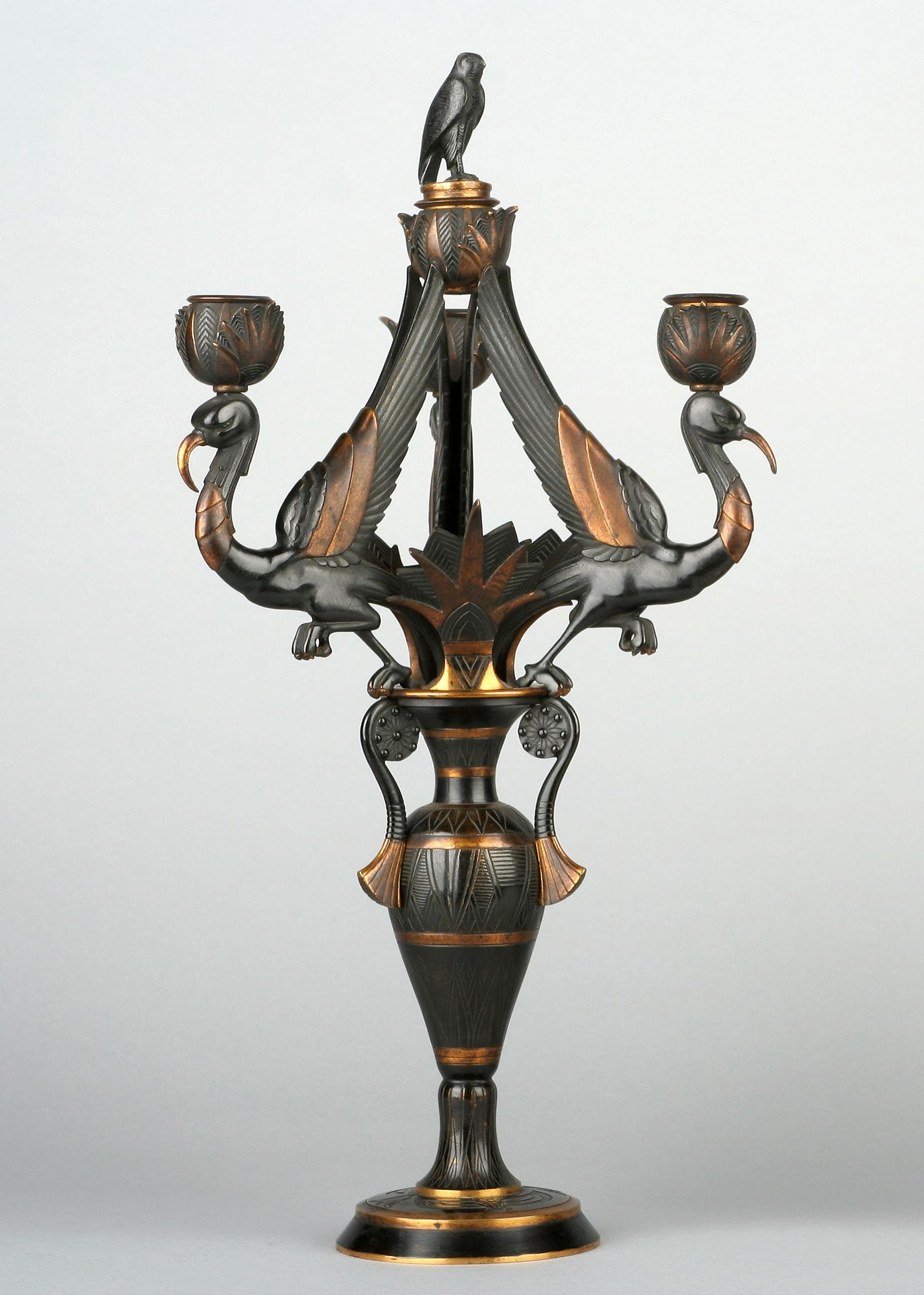 Rare pair of Egyptian style candelabras attributed to G. Servant, made in two patina bronze. Cast in form of an antique vase surmounted by three leaned ibis birds, each topped by a light nozzle. Decorated with lotus flower, winged beetles and