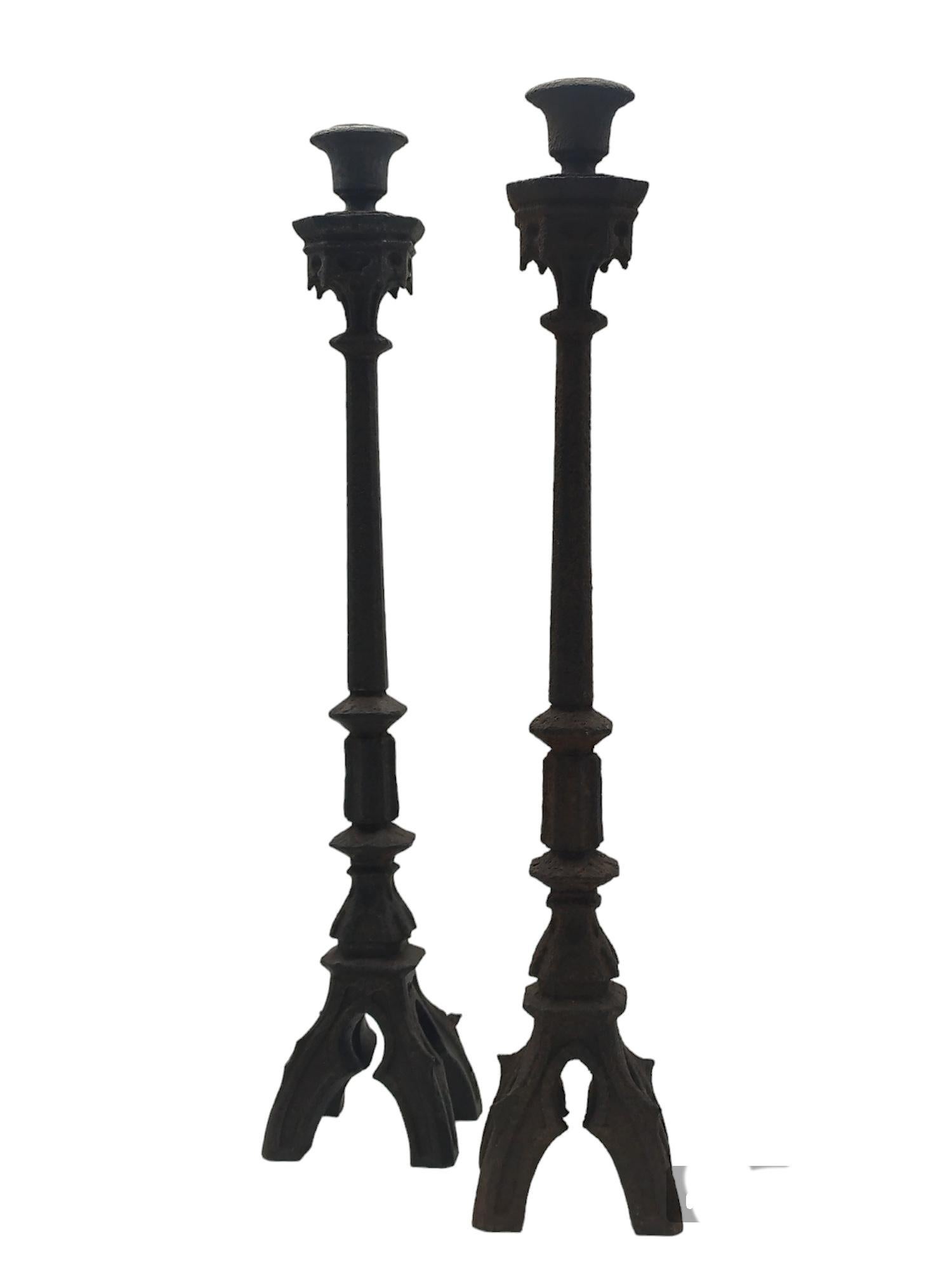 Pair of iron candlesticks in Italian neo-Gothic style with four-foot metal bases. Good overall condition, with excellent patina, wear commensurate with age and use.