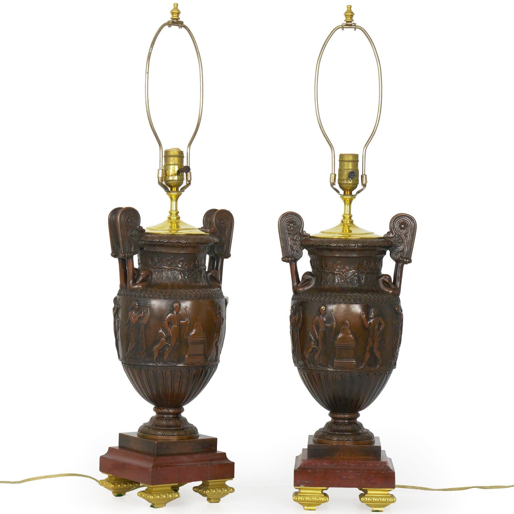 A handsome pair of lamps likely designed after the Olympian deities of the Greek pantheon, this finely cast pair of patinated bronze lamps are in the form of an Amphora vases with a turned brass cap through which the electrical element projects.