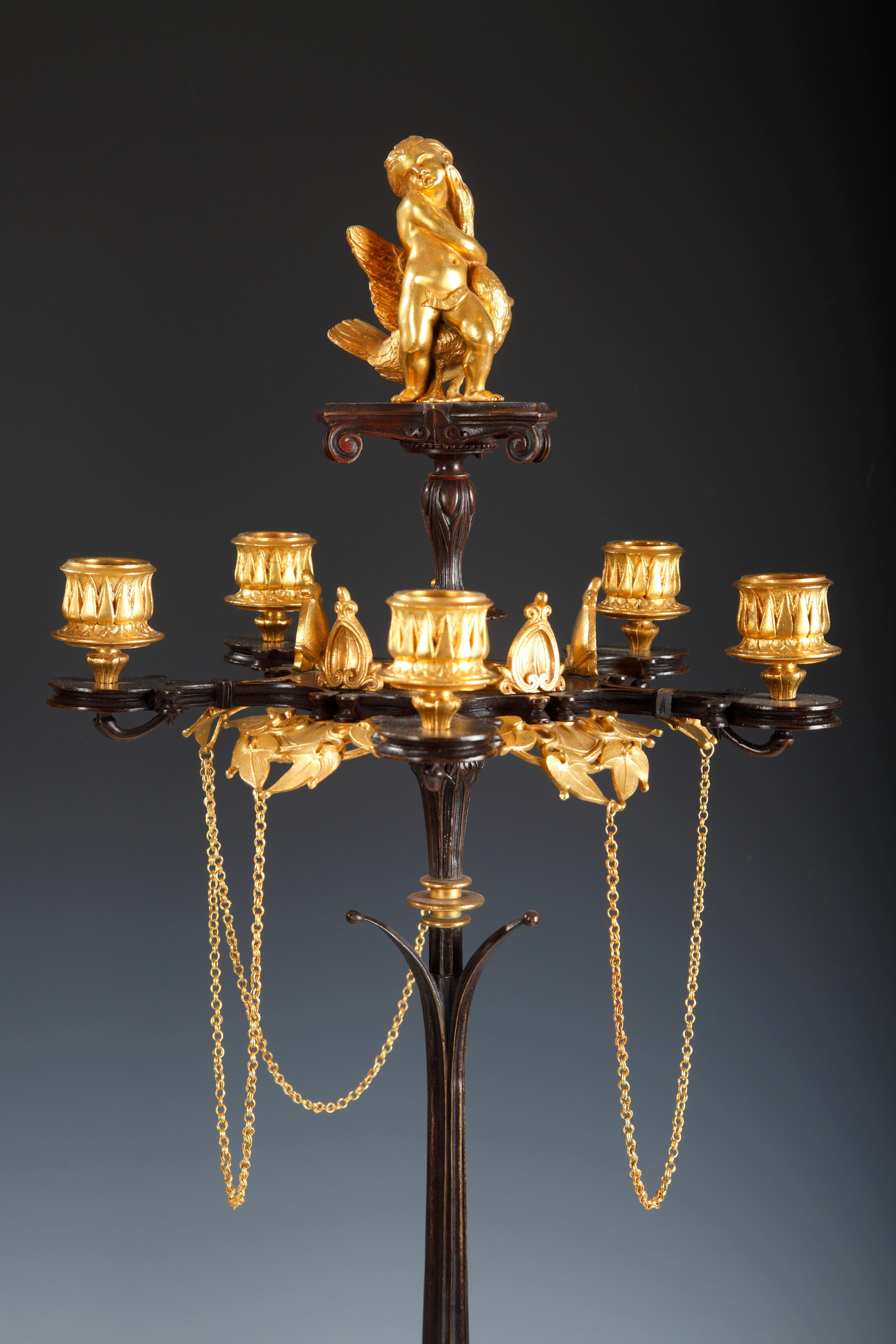 A very Fine pair of Greek style patinated and gilded bronze figural candelabras attributed to V. Paillard ; each presenting six light arms ornamented with ivy leaves and Fine chains, supported by a grooved stem and a tripod base decorated with
