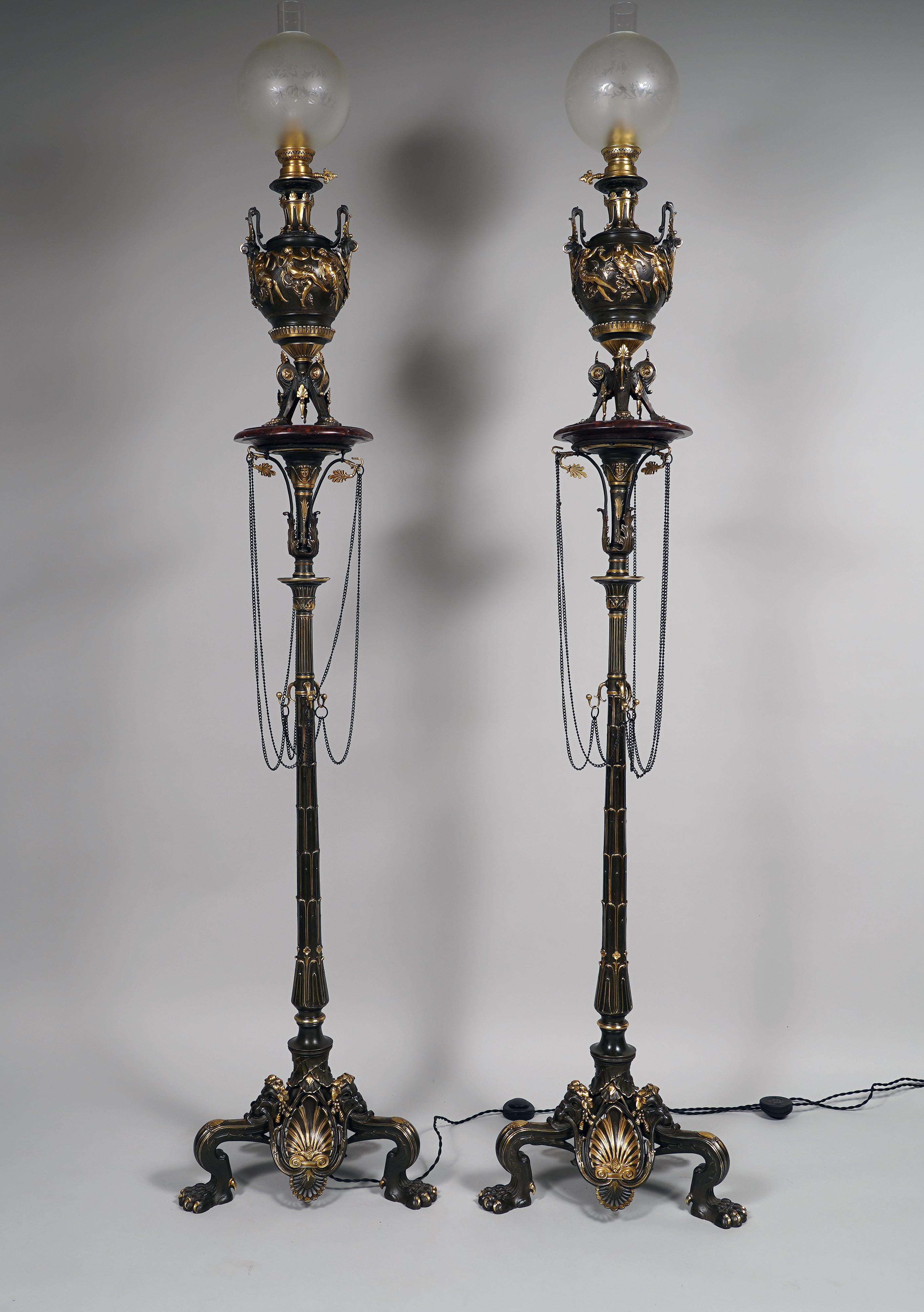 Measures : Total Height : 188,5 cm (74,2 in.) ; Base : 45 x 45 cm (17,7 x 17,7 in.)
Pedestal height : 136 cm (53,5 in.)
Lamp height : 52 cm (20,4 in.)

Beautiful pair of neo-Greek floor lamps in bronze with double patina, composed of lamps in the