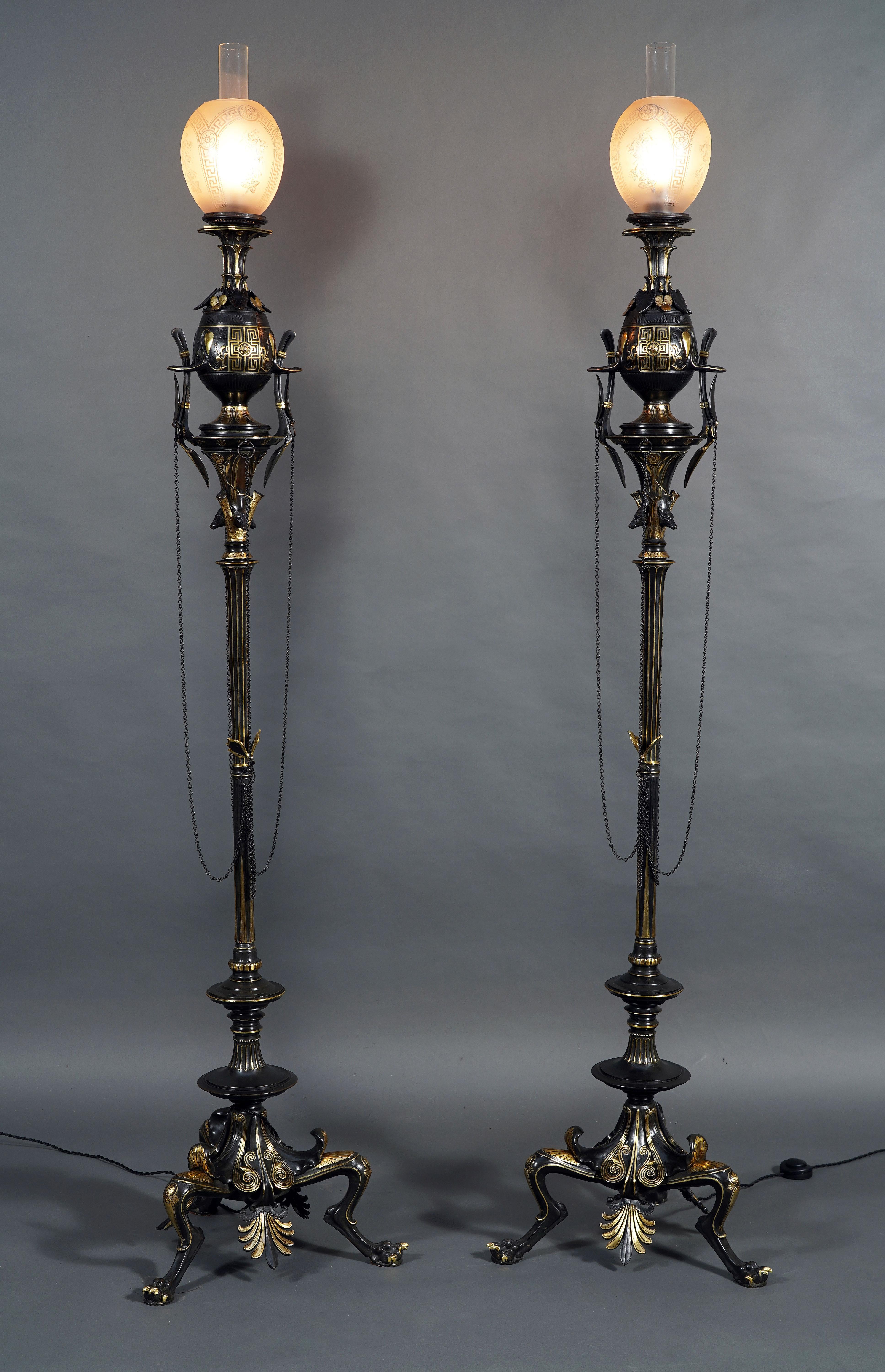 Rare paire de lampadaires de style grec en bronze patiné attribués à G. Servant, chacun surmonté d'un globe en verre dépoli gravé d'étoiles et d'une frise de motifs grecs. Le corps du vase, décoré de motifs de style grec tels que des palmettes, une