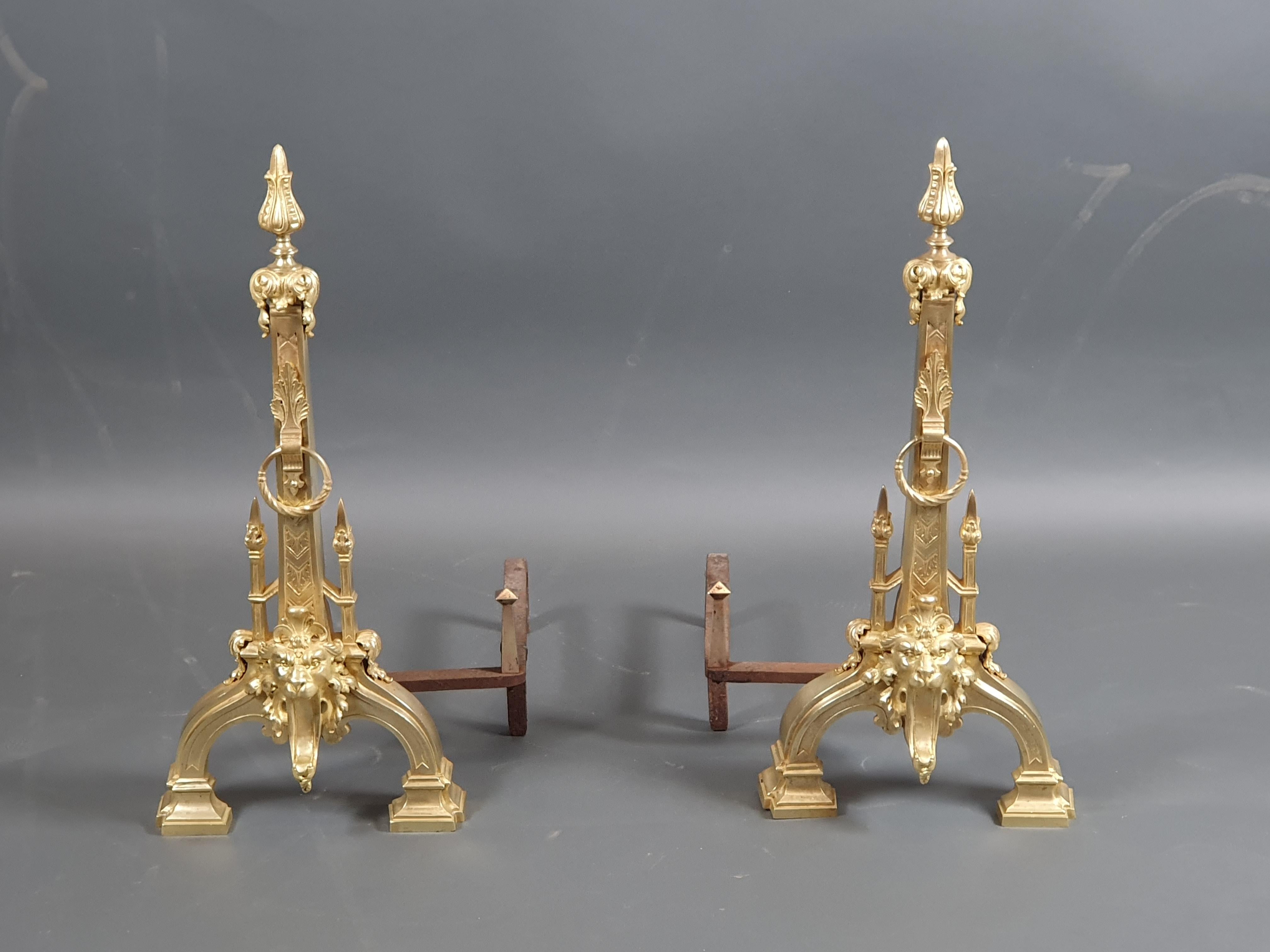 Magnificent pair of cathedral andirons of neo-renaissance inspiration in gilt bronze, adorned with a roaring lion's head surmounted by an obelisk-shaped spire.

The irons are thick and original, they are adorned with a gilded bronze