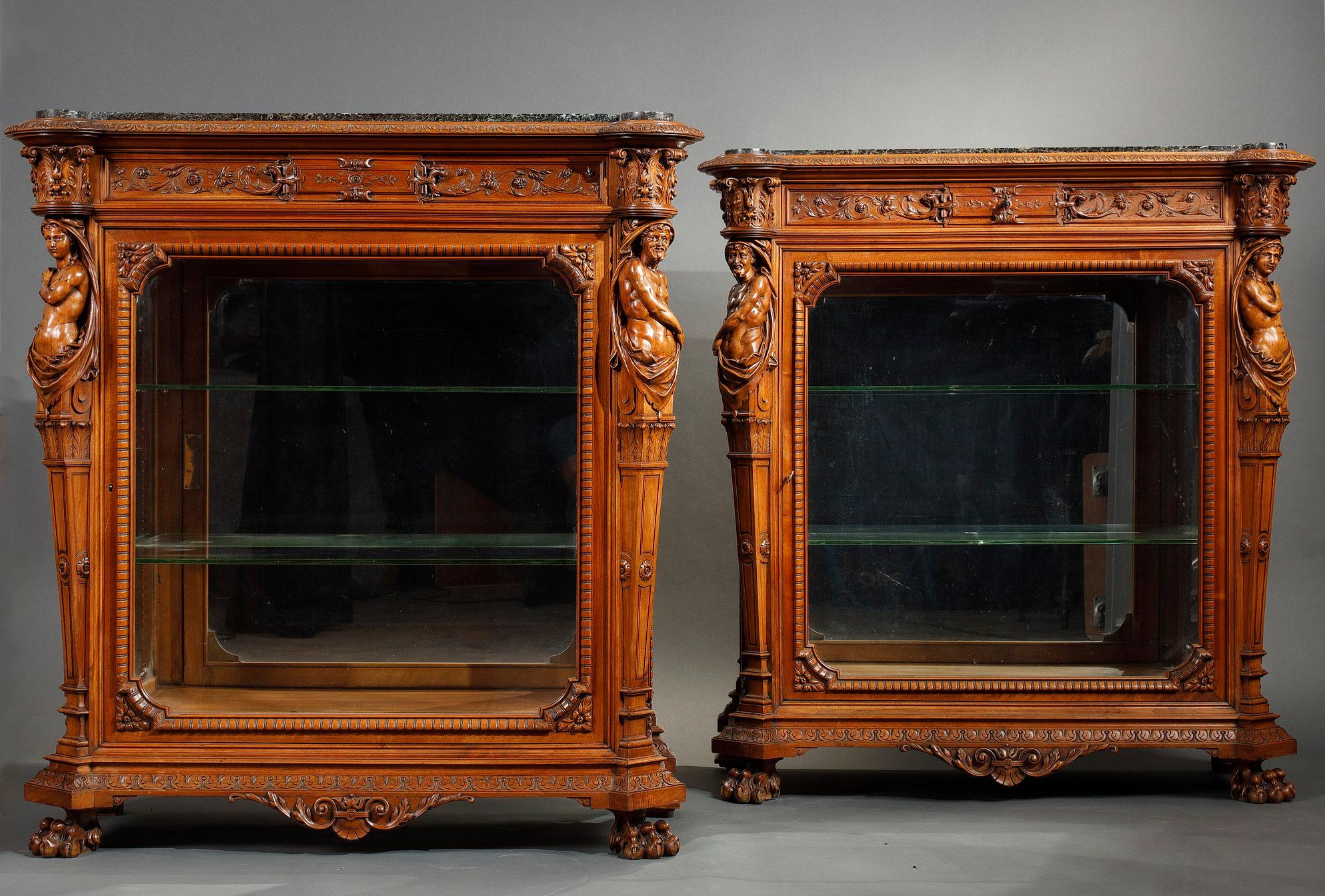 Fine pair of neo-Renaissance vitrines in richly carved wood, with three glazed sides framed by a relief frieze. Each opening to a drawer decorated with interlacing on the belt, and to a front door, they have two glass shelves. The uprights are
