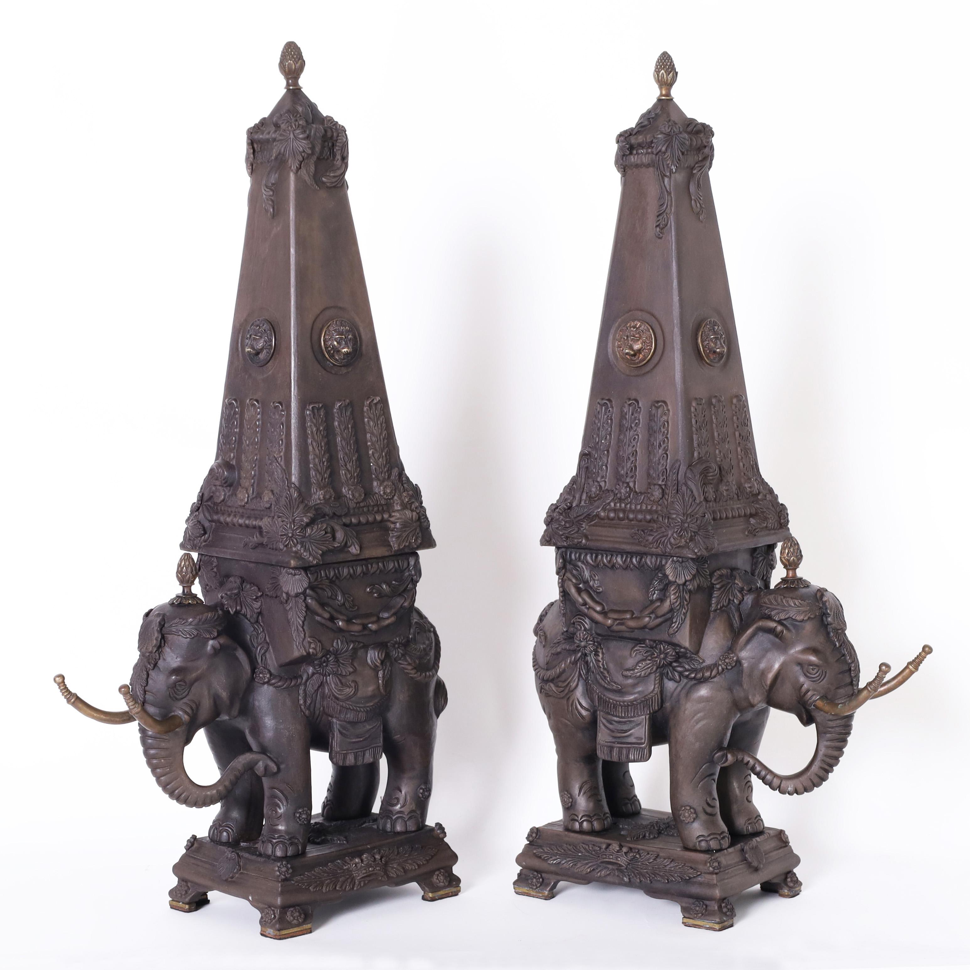 Vintage pair of Italian neoclassic garnitures or objects of art depicting elephants carrying obelisks, crafted in ceramic or earthenware with a bisque finish and highlighted with bronze finials, lion heads and tusks.