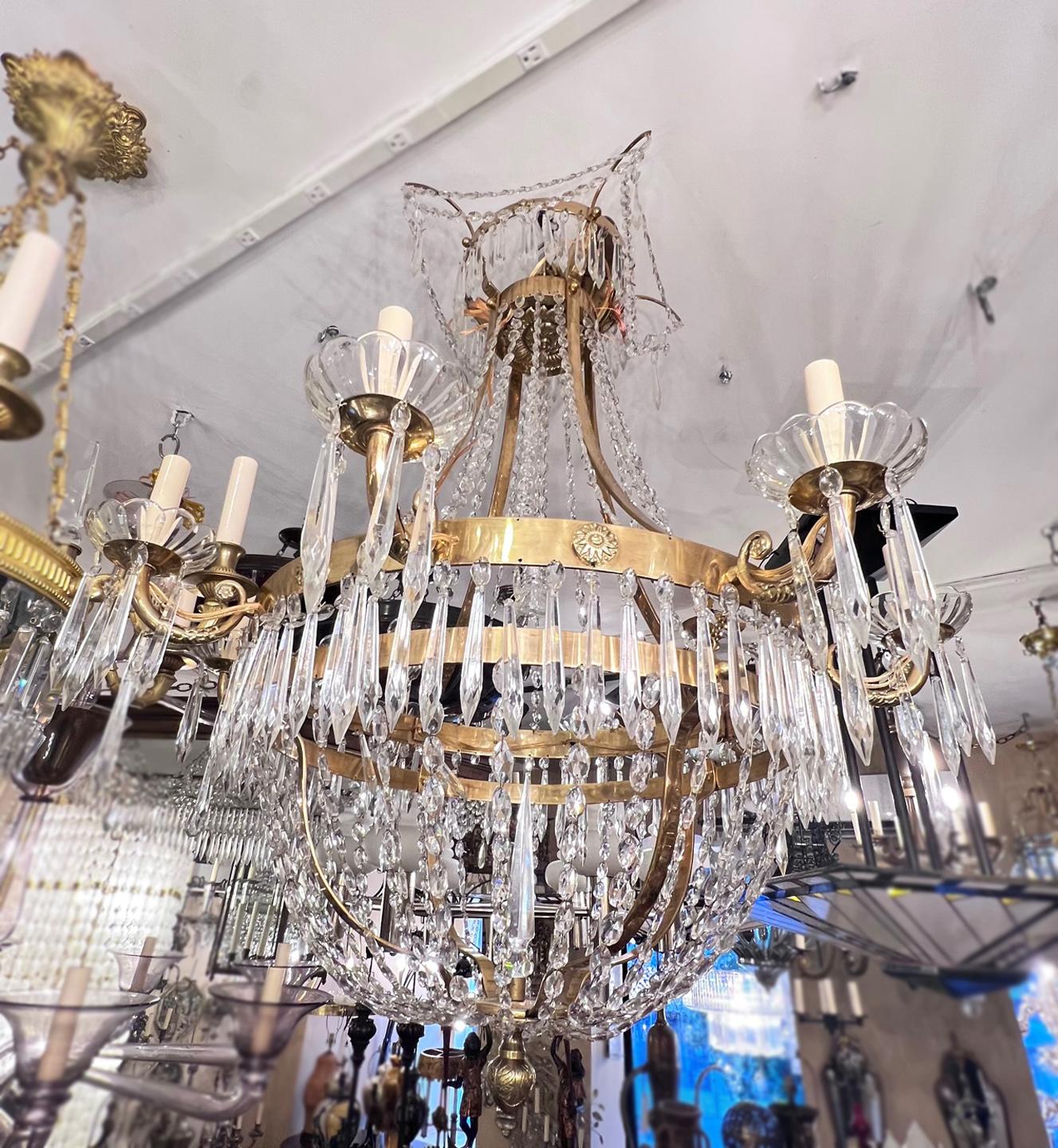 A pair of circa 1920's eight-arm neoclassic style gilt bronze Swedish chandeliers with crystal pendants and original patina. Sold individually.

Measurements:
Diameter: 30